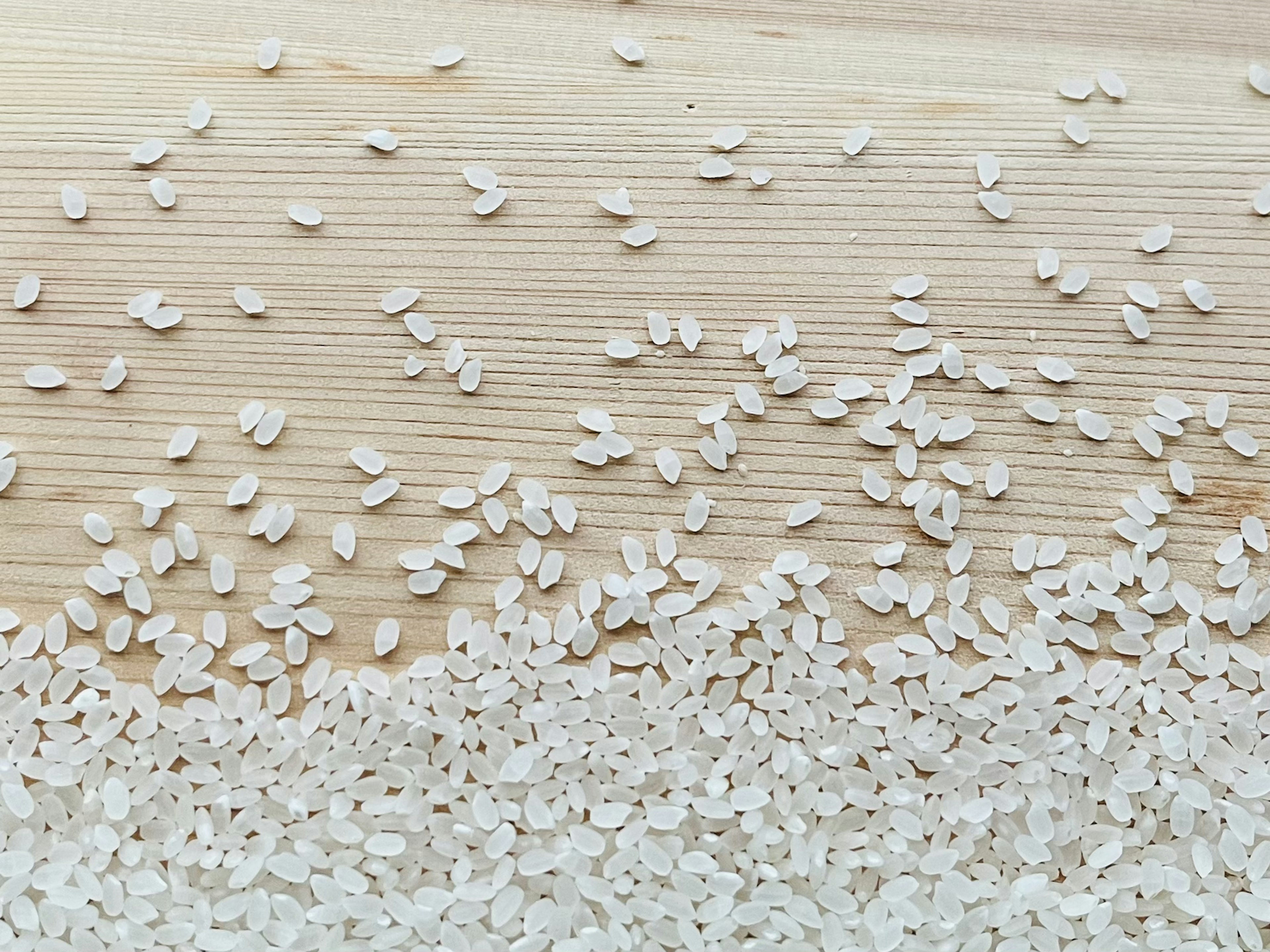 White rice grains scattered on a wooden surface