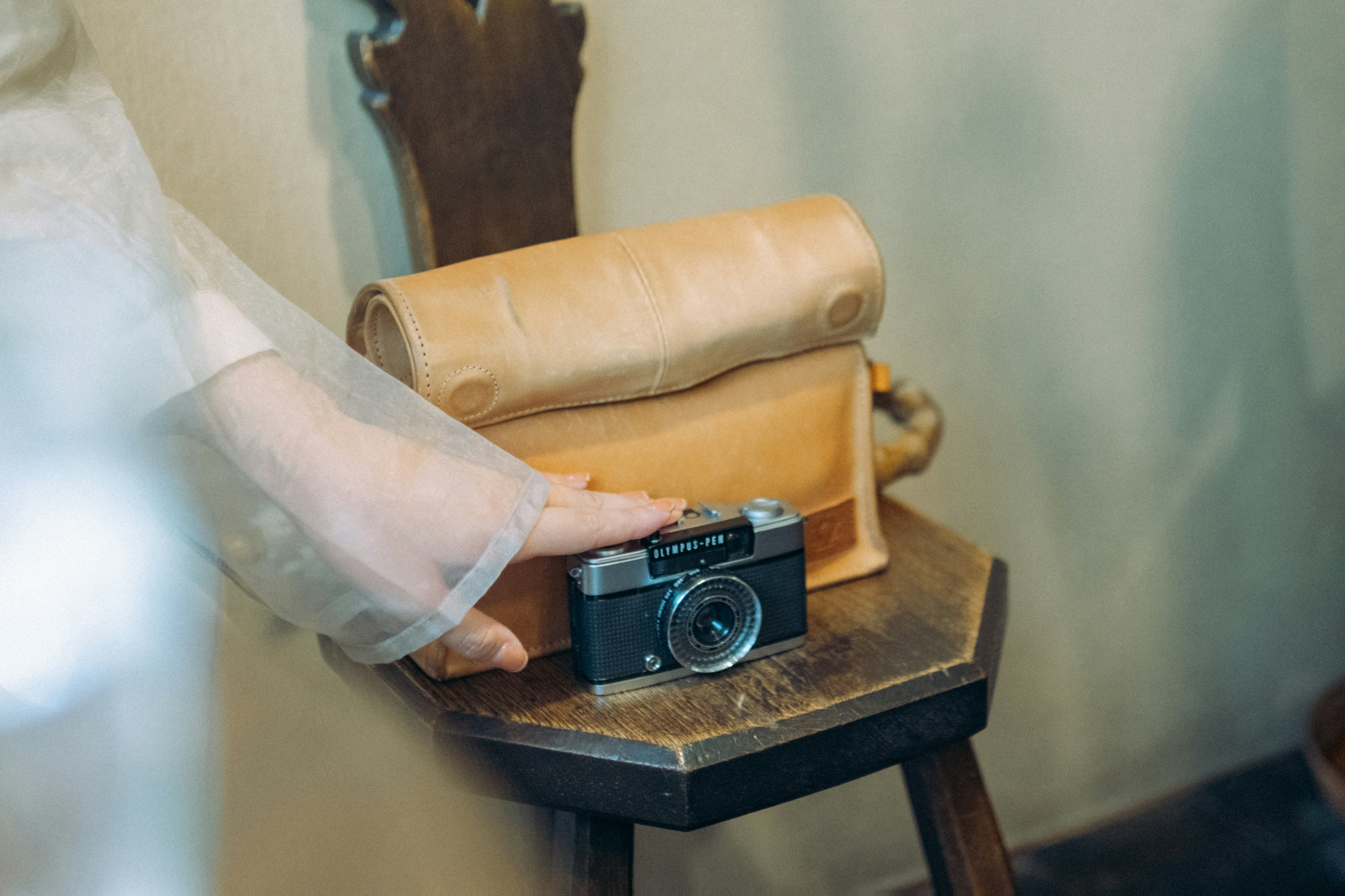 Cámara clásica sobre una mesa de madera junto a una bolsa de cuero