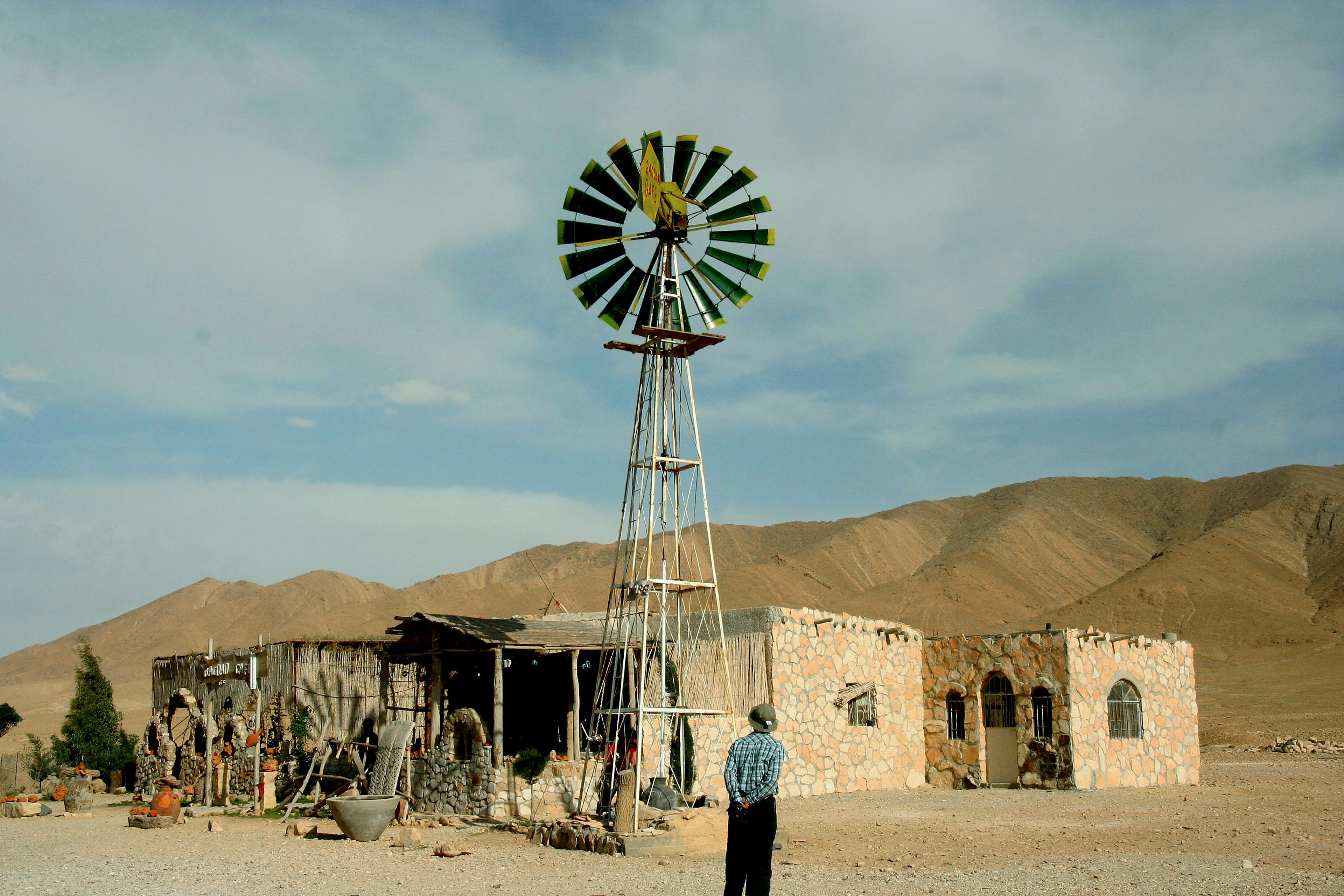 Landscape featuring a windmill and dilapidated buildings