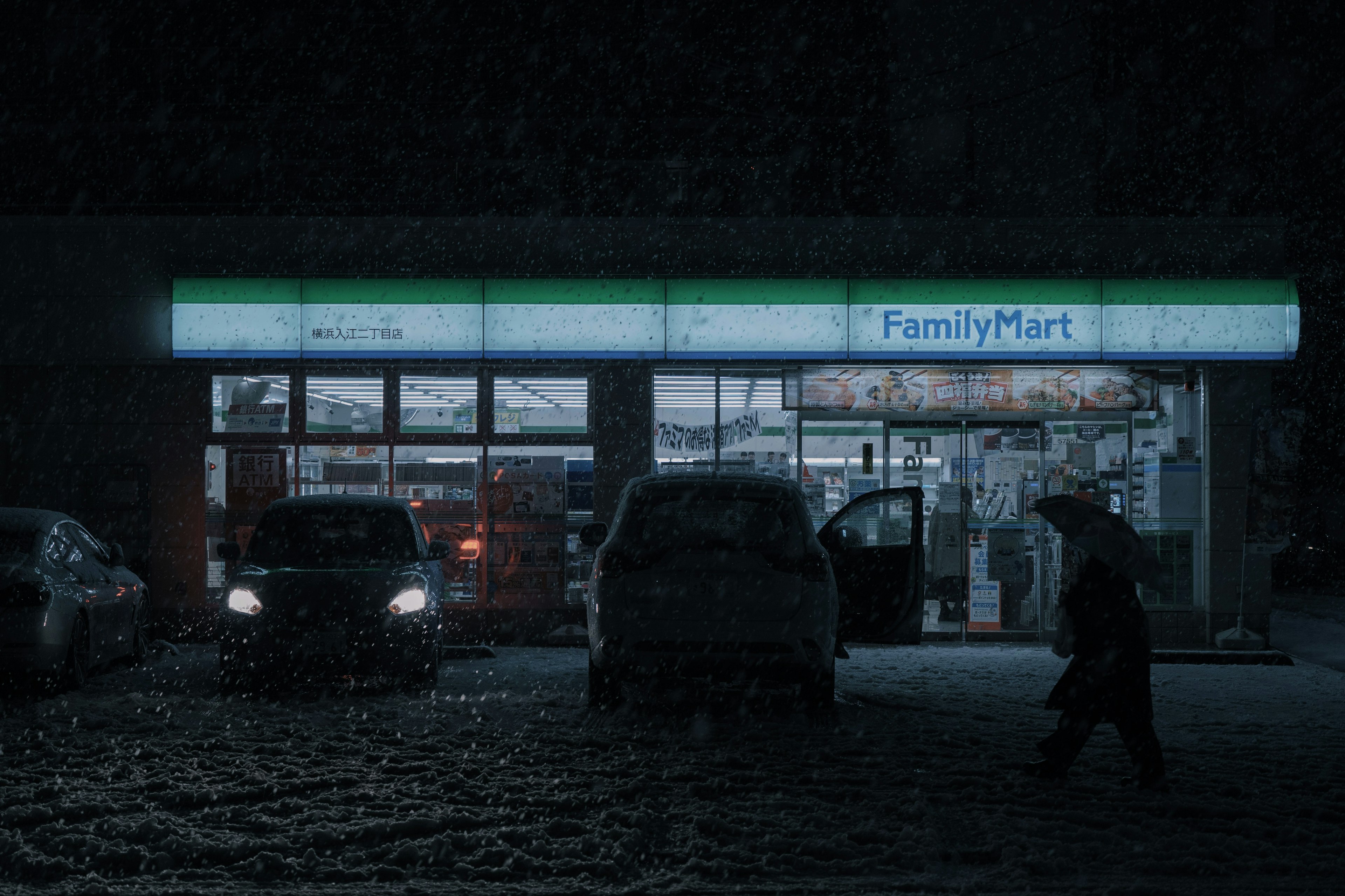 Extérieur de FamilyMart sous la neige avec une personne marchant