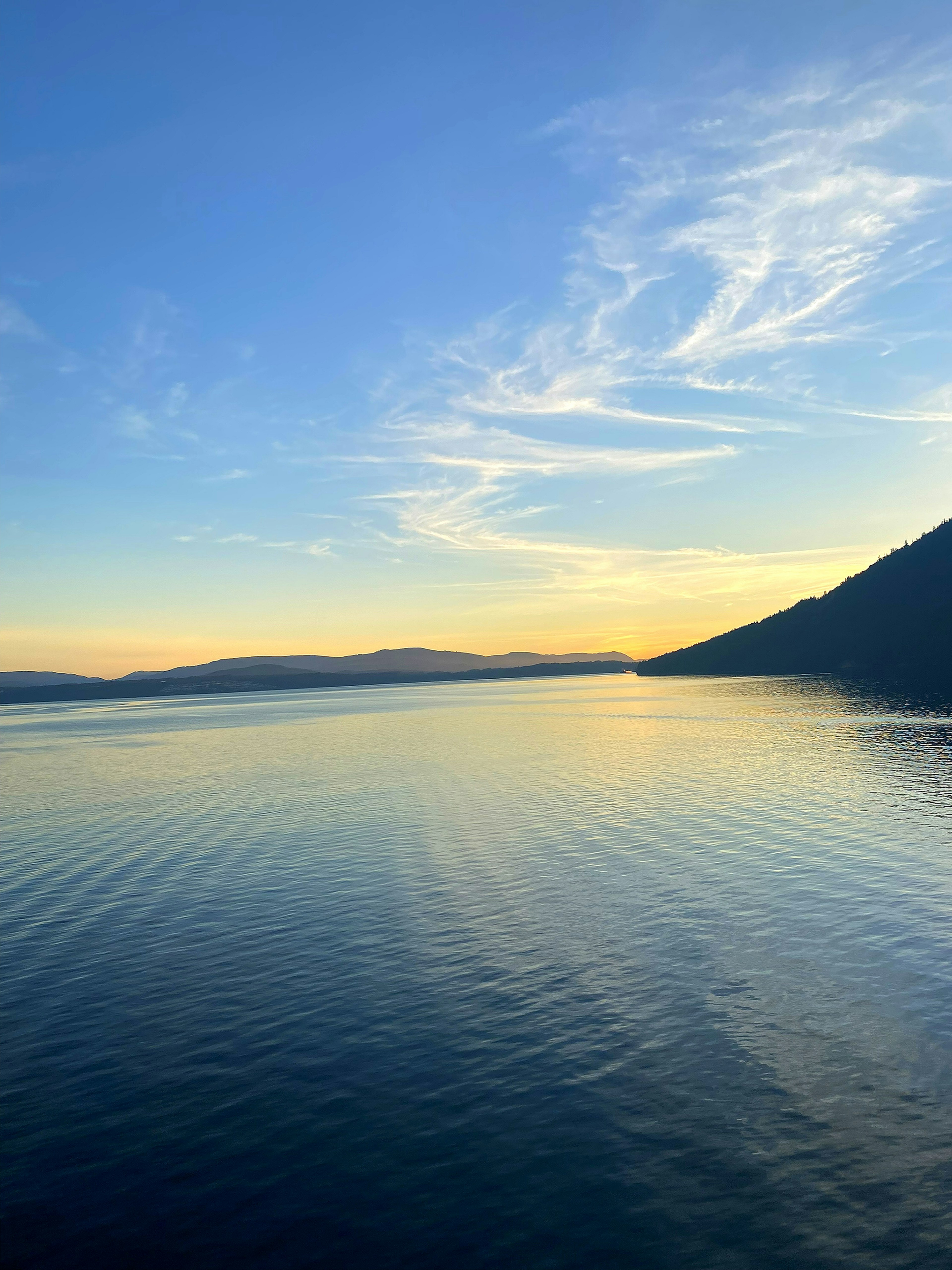 Superficie d'acqua serena sotto un cielo blu al tramonto