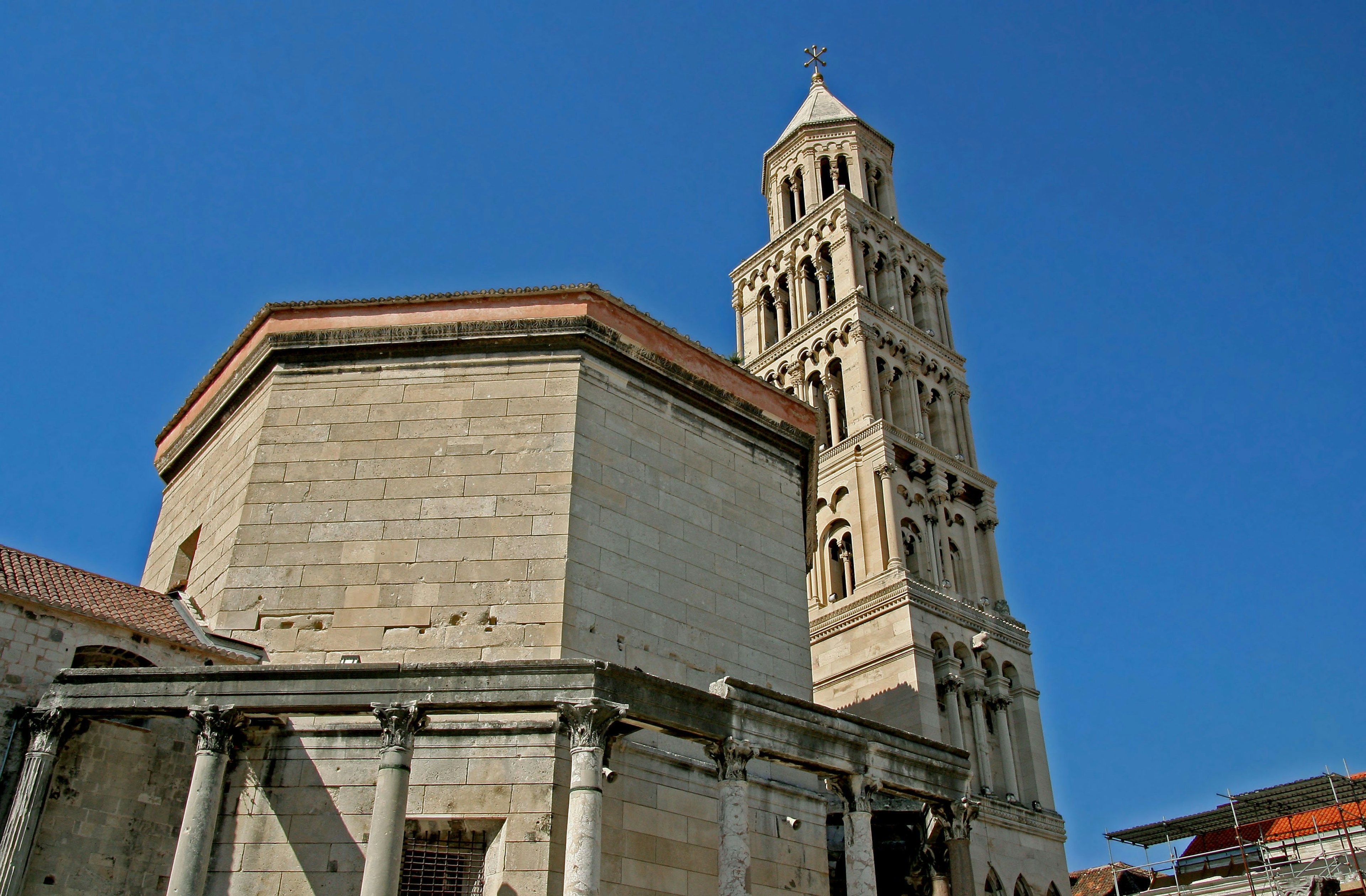 Blick auf den Glockenturm des Diokletianpalastes und ein Steingebäude unter klarem blauen Himmel