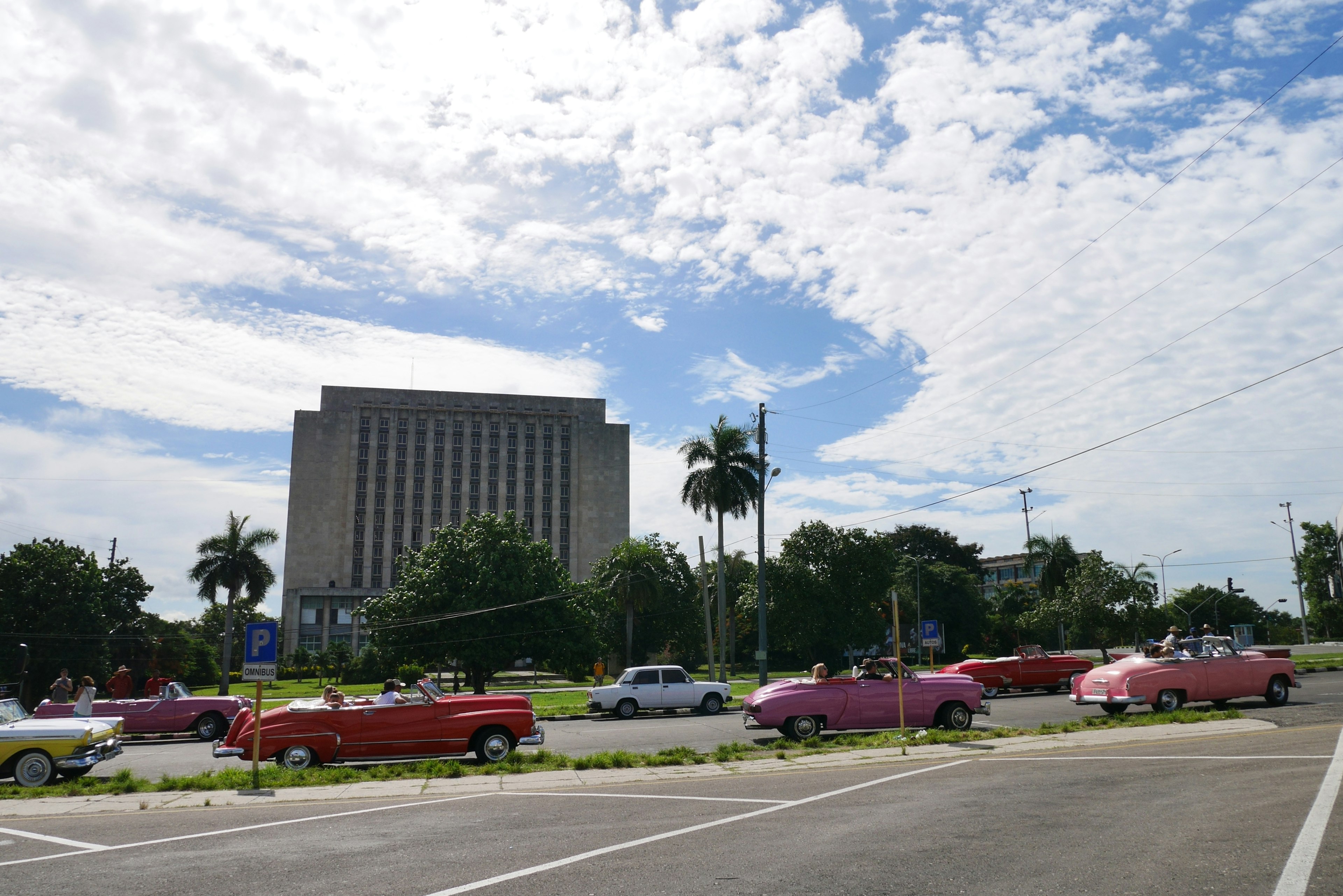 Autos clásicos coloridos alineados en la calle con cielo azul