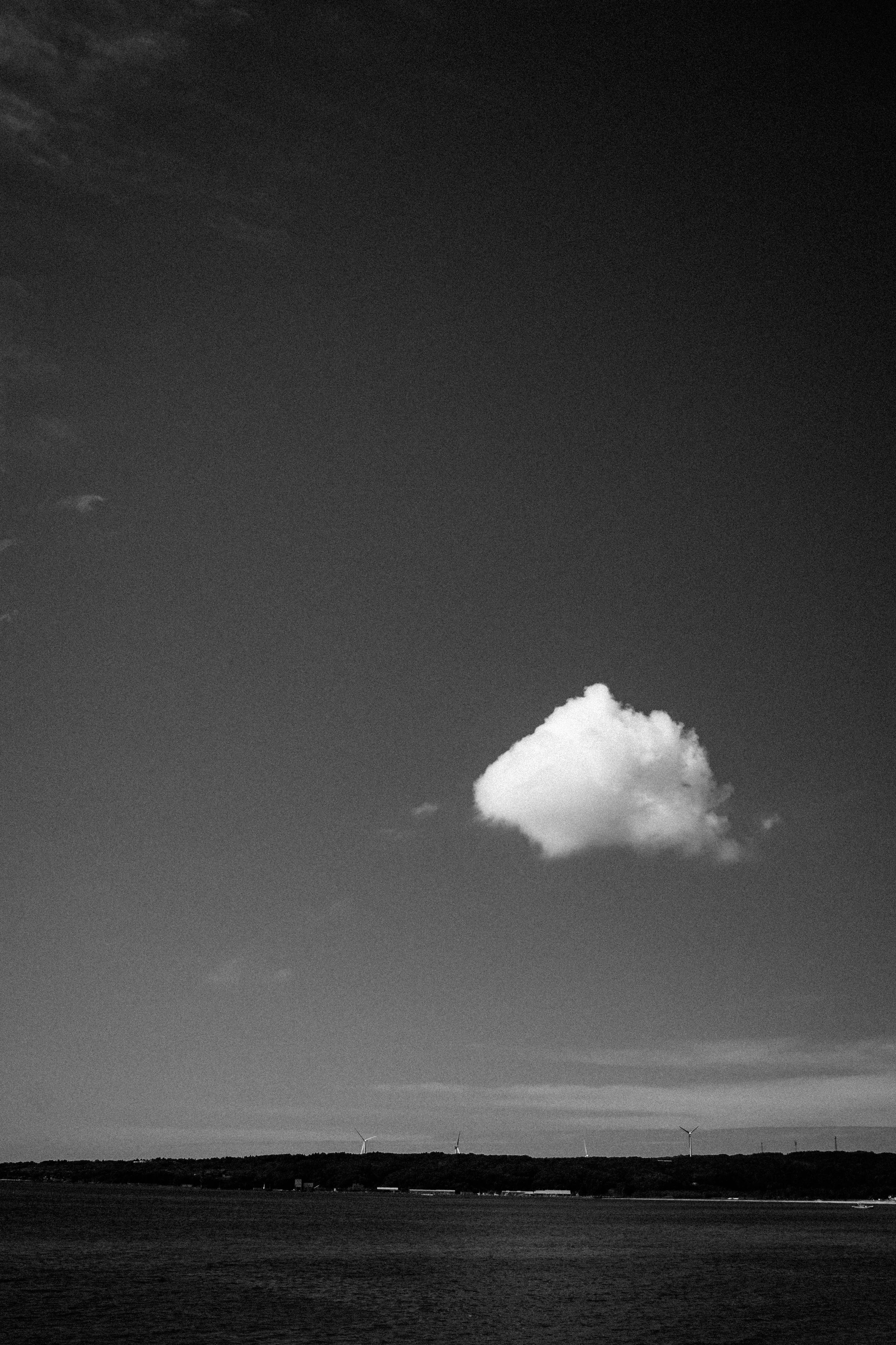 Una sola nube blanca en un cielo azul capturada en blanco y negro