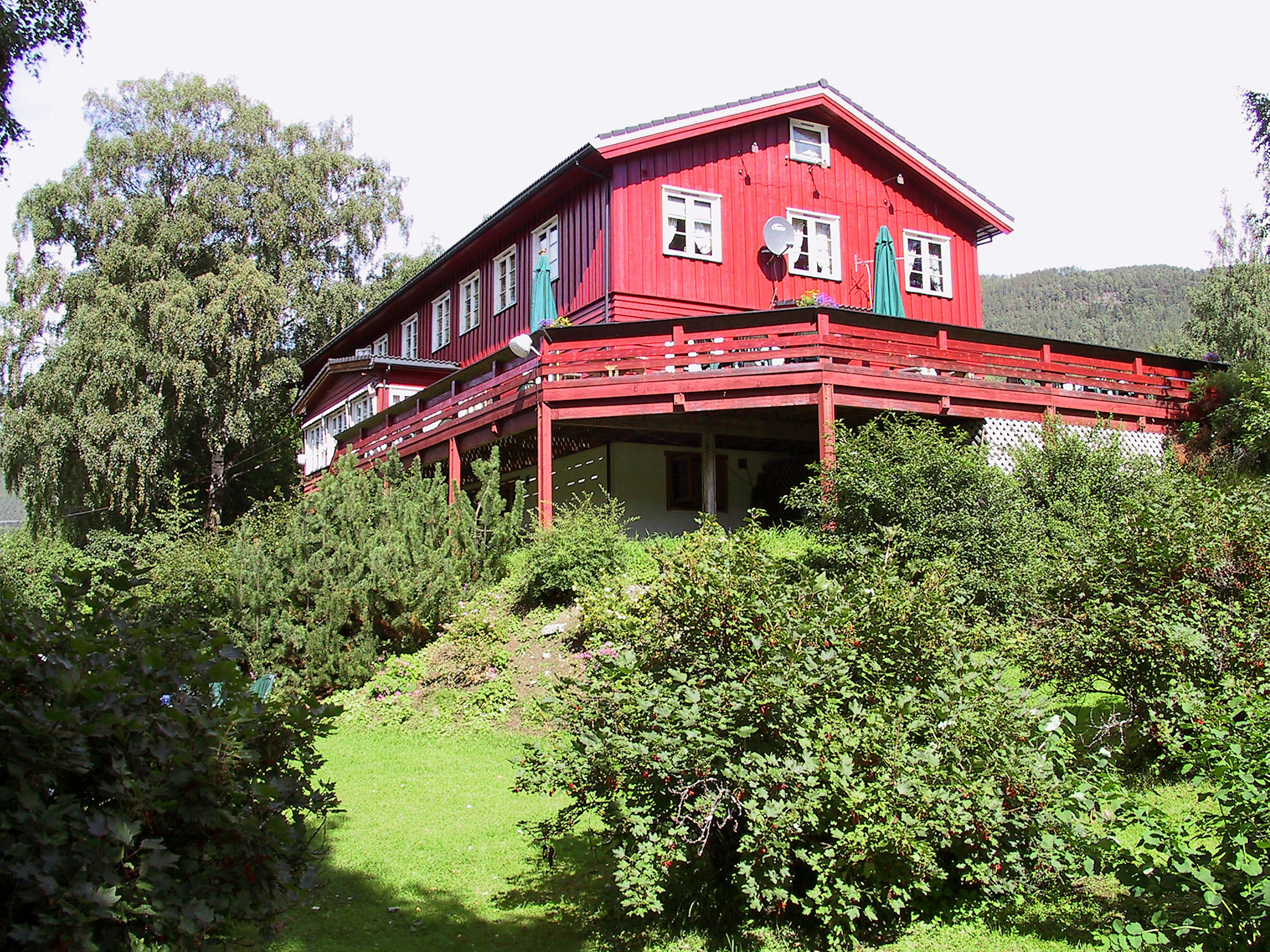 Traditionelles rotes Holzhaus mit grünem Rasen und umgebender Vegetation