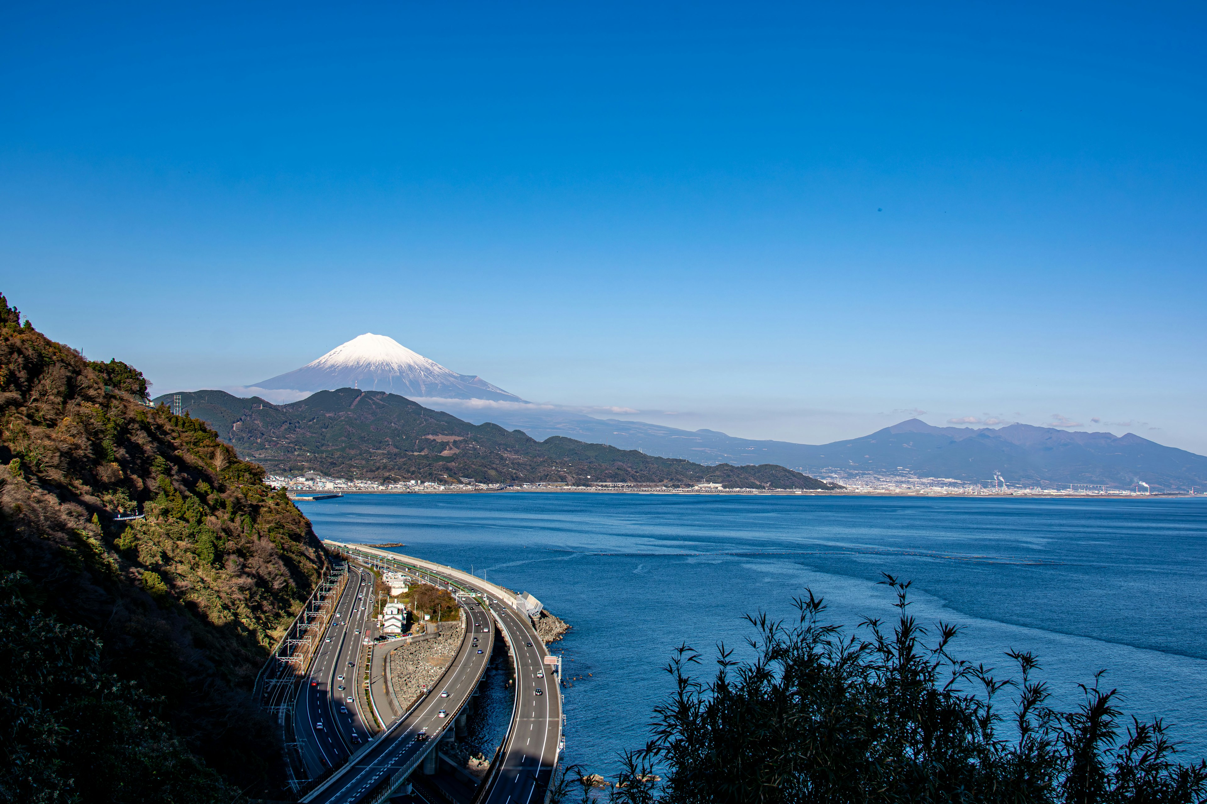 Vue pittoresque du mont Fuji sous un ciel bleu avec l'océan et une voie ferrée le long de la côte