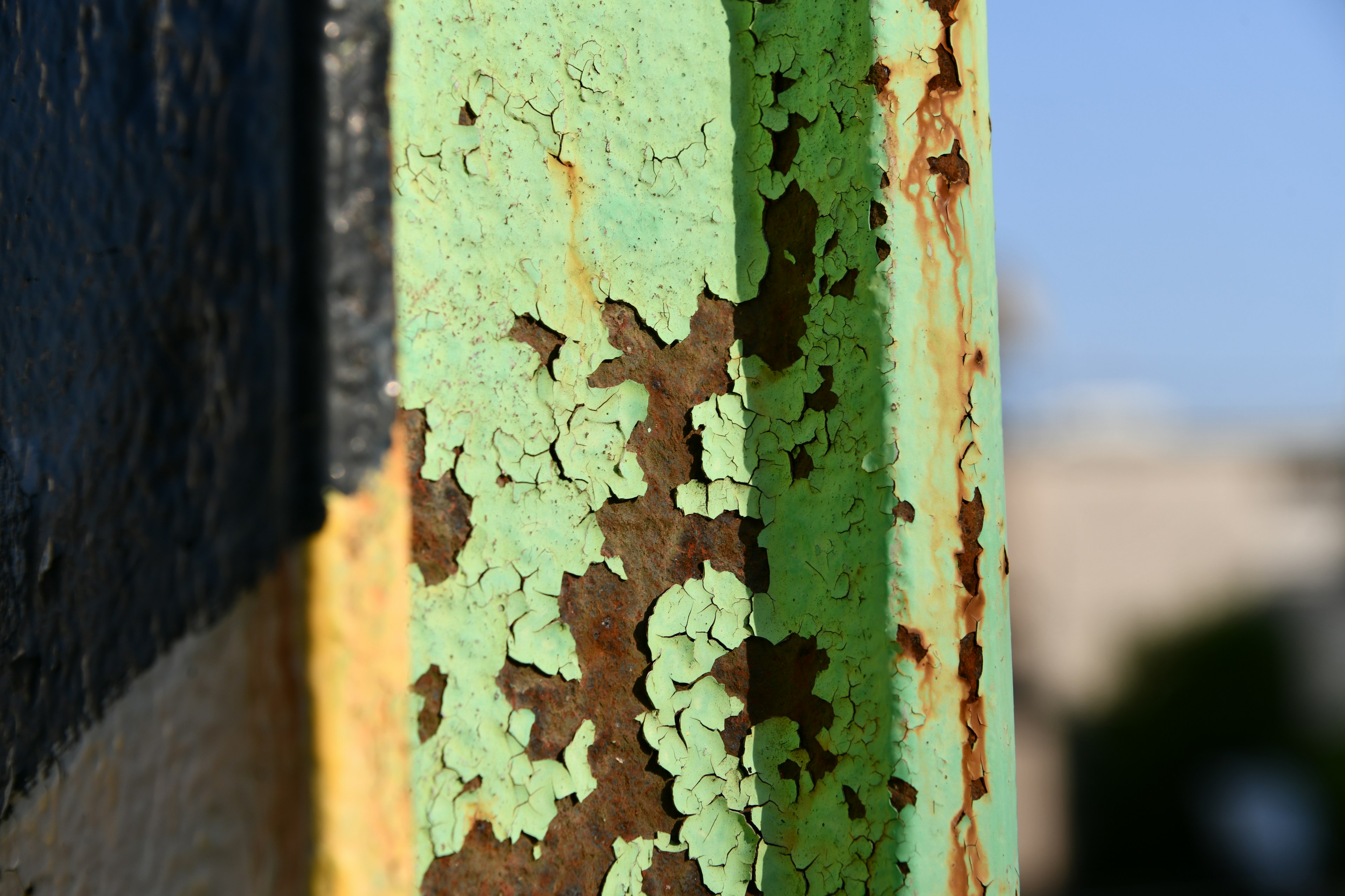 Textured peeling paint on a green and brown metal surface