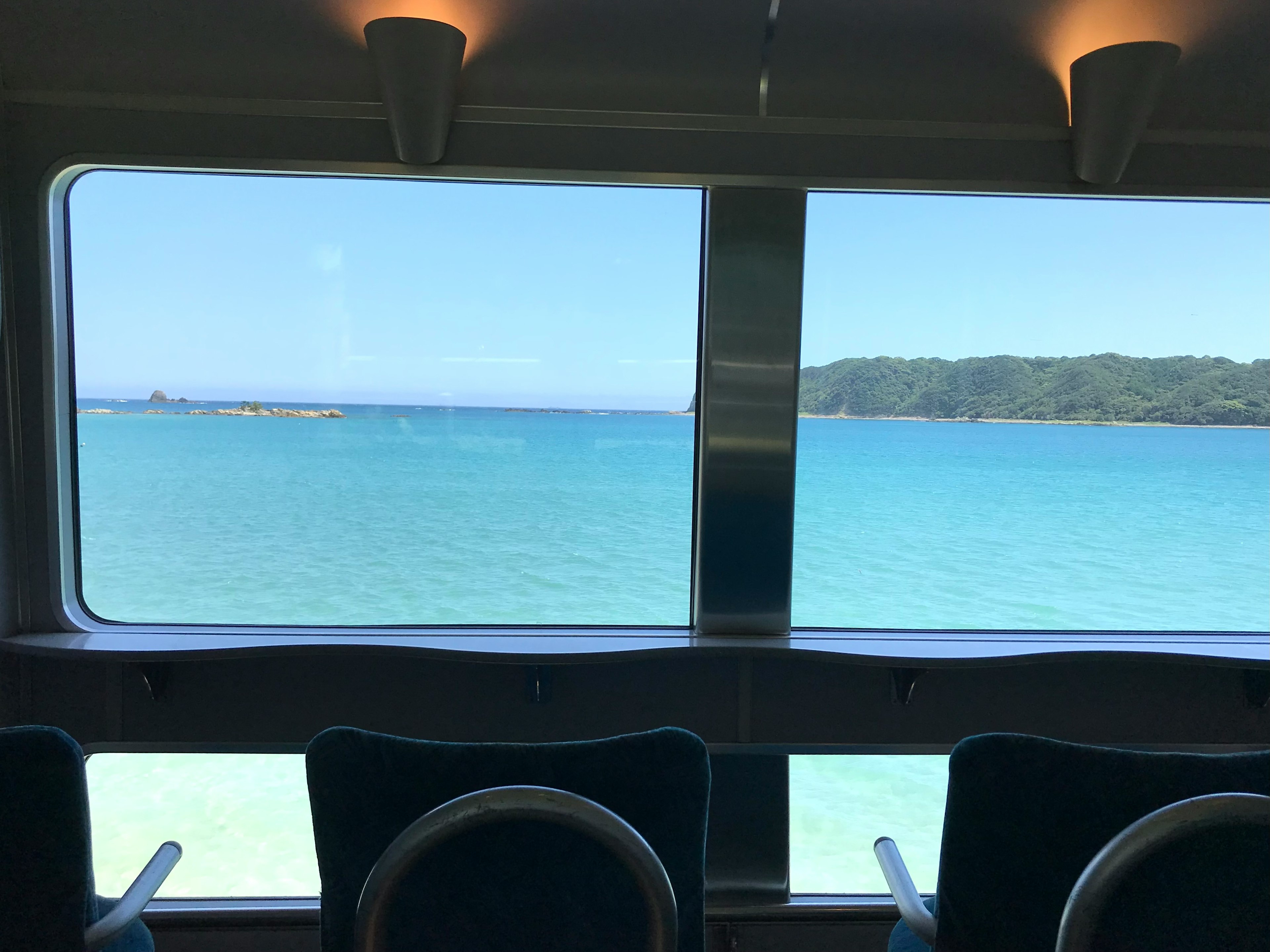 Vue intérieure d'un bateau avec une mer bleue et des montagnes visibles à travers la fenêtre