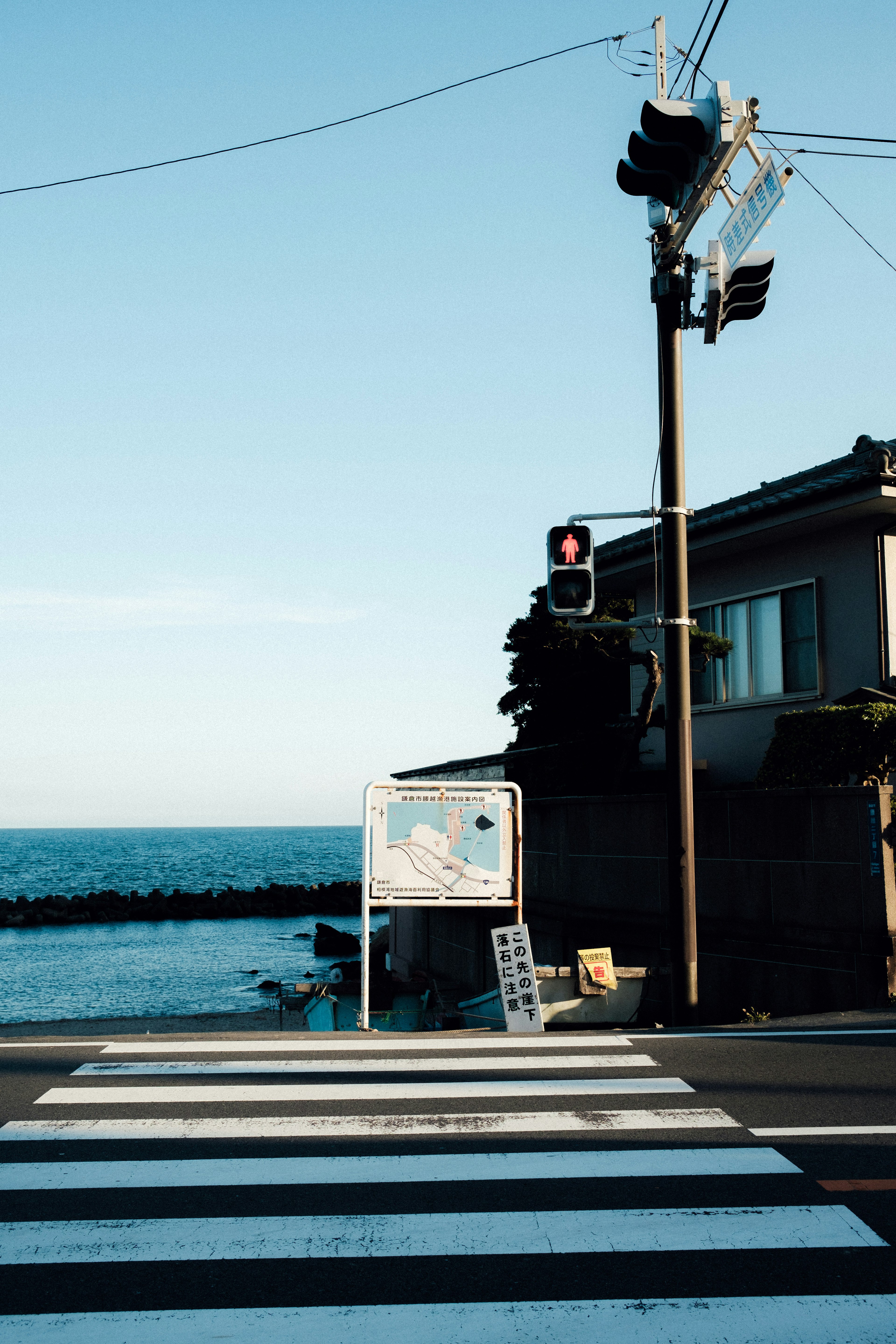 Crosswalk and traffic signal at a street corner with blue ocean and sky in the background