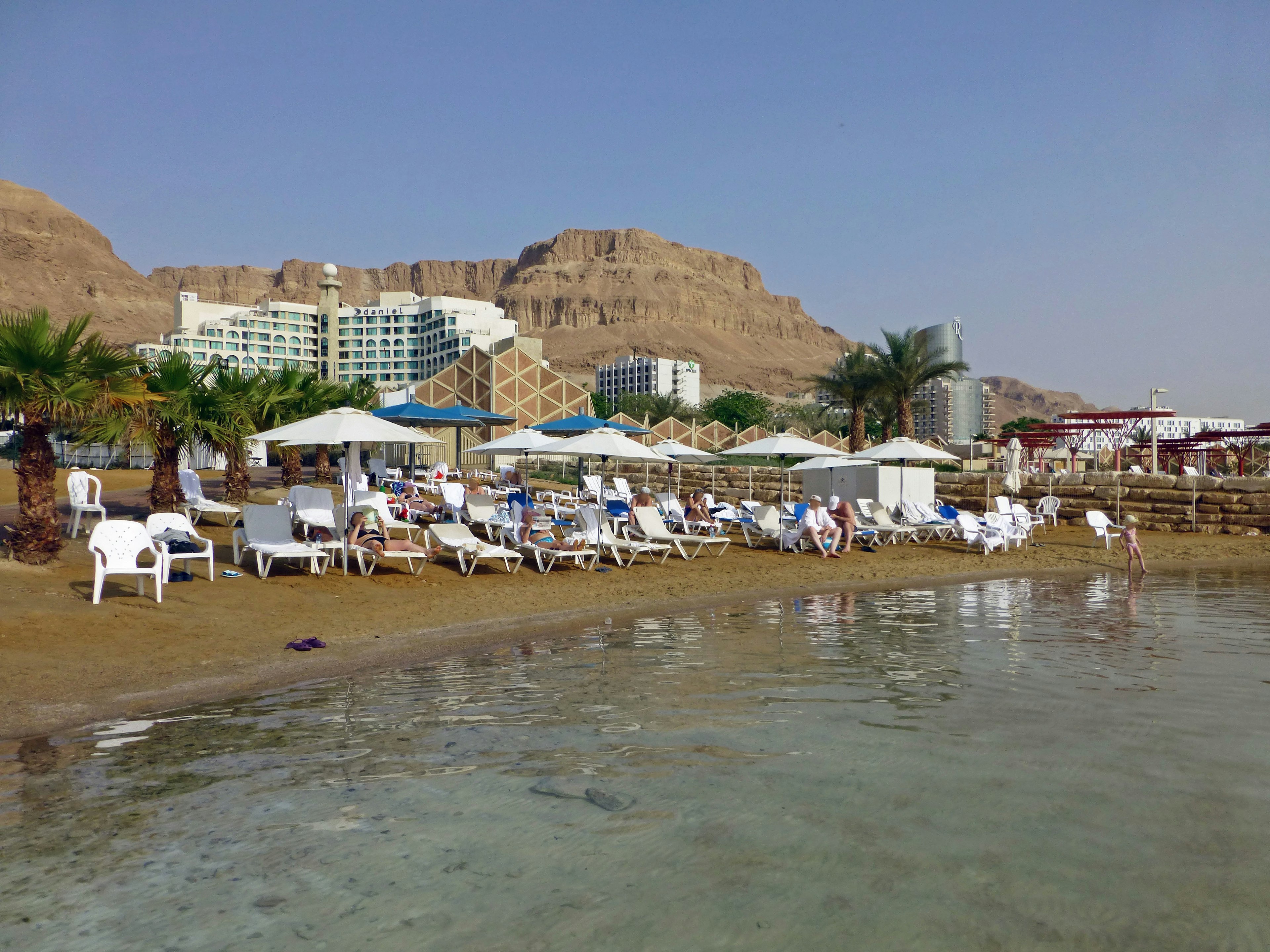 Eine Strandansicht mit weißen Sonnenschirmen und Liegen am Ufer