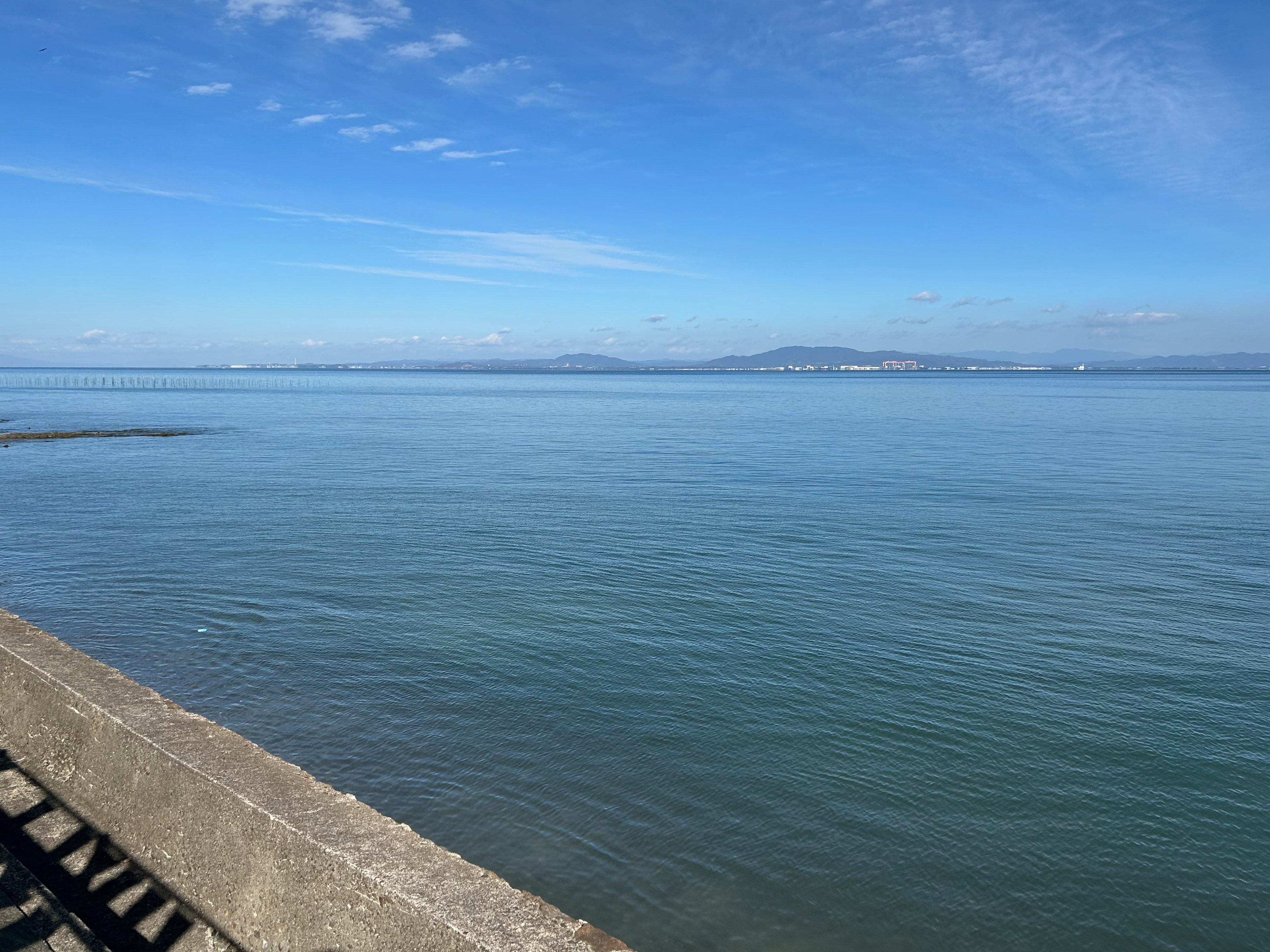 Calm sea and blue sky landscape with a concrete pier in the foreground