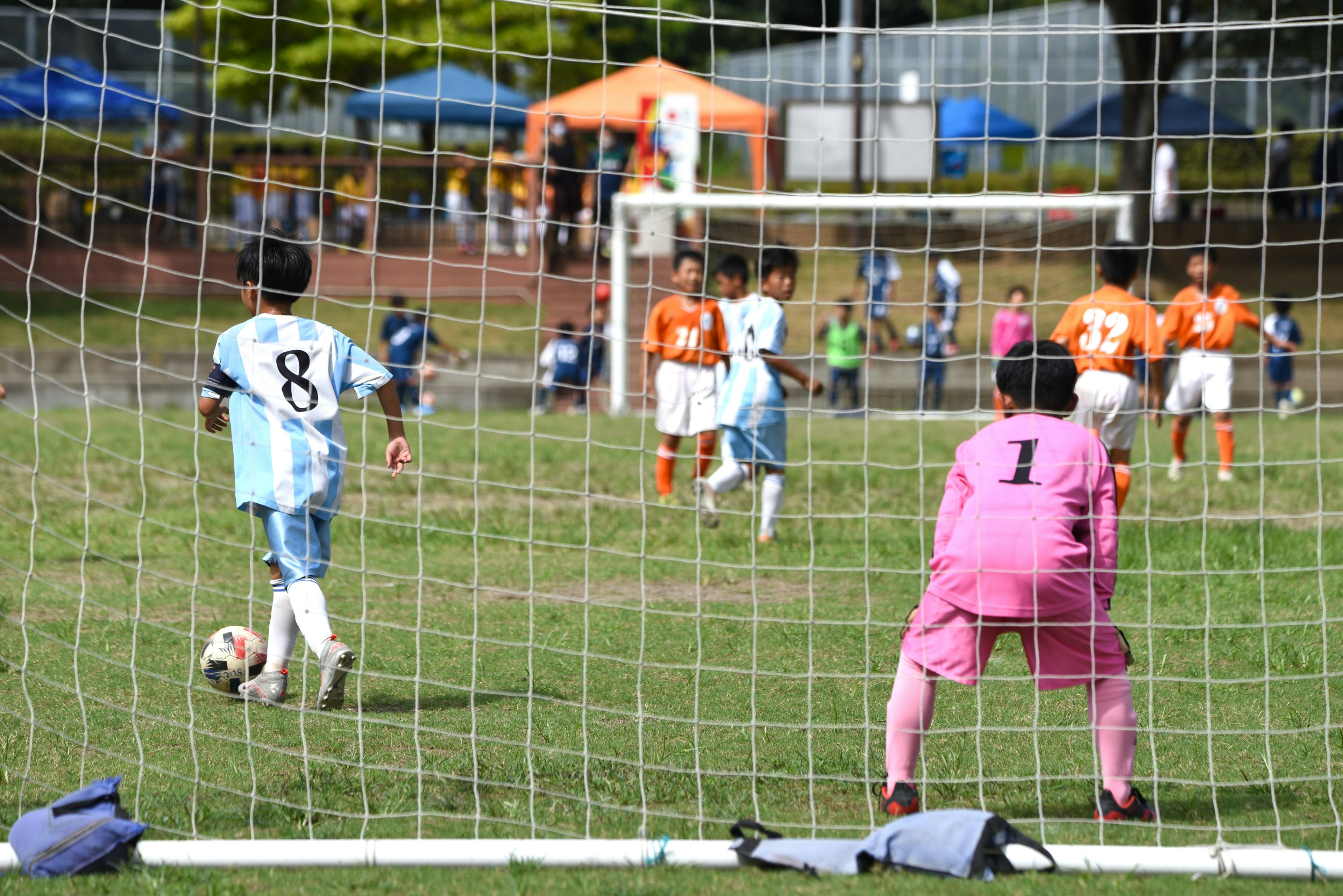 Partido de fútbol con un jugador persiguiendo el balón y un portero en acción