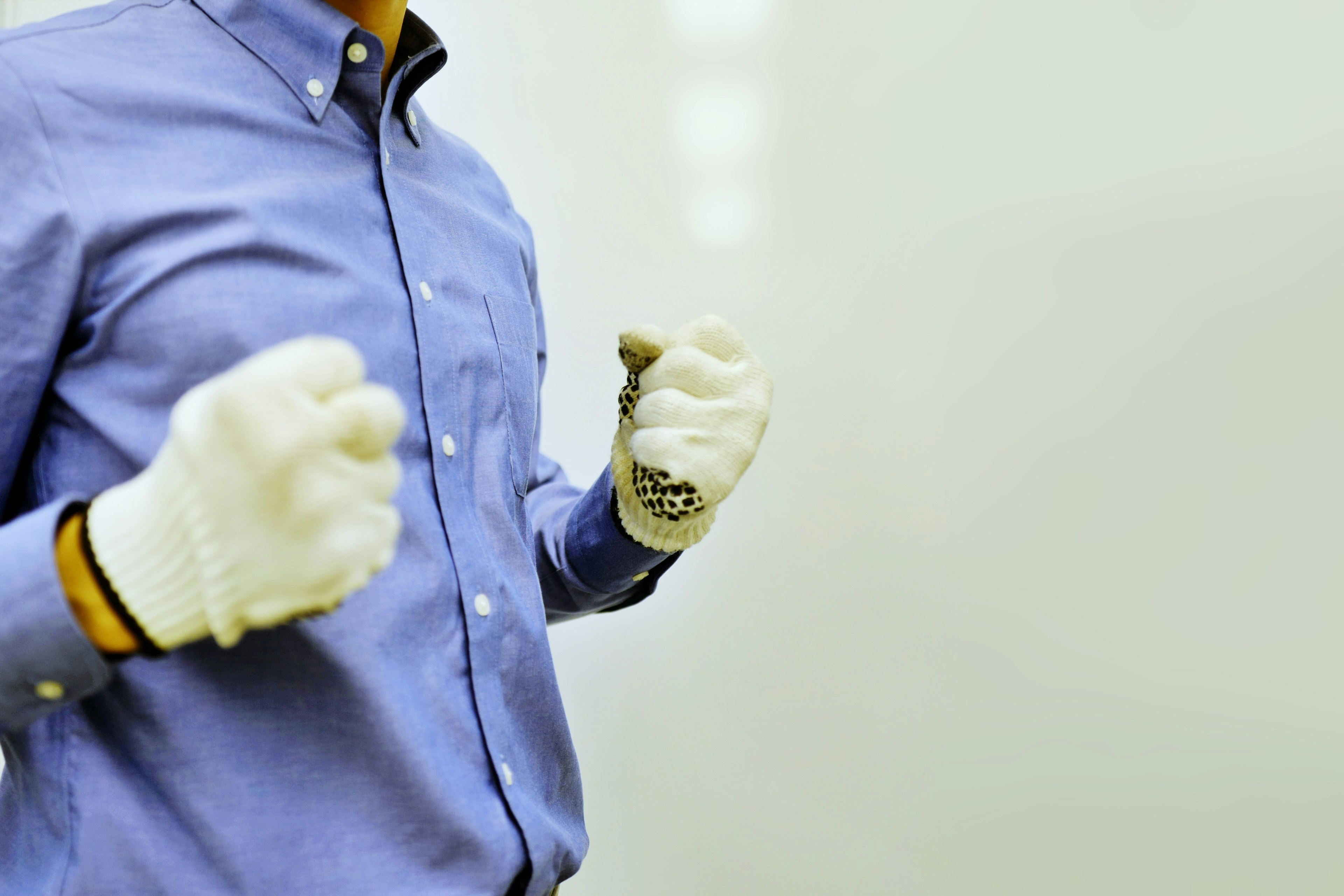 Un uomo in camicia blu stringe le mani guantate