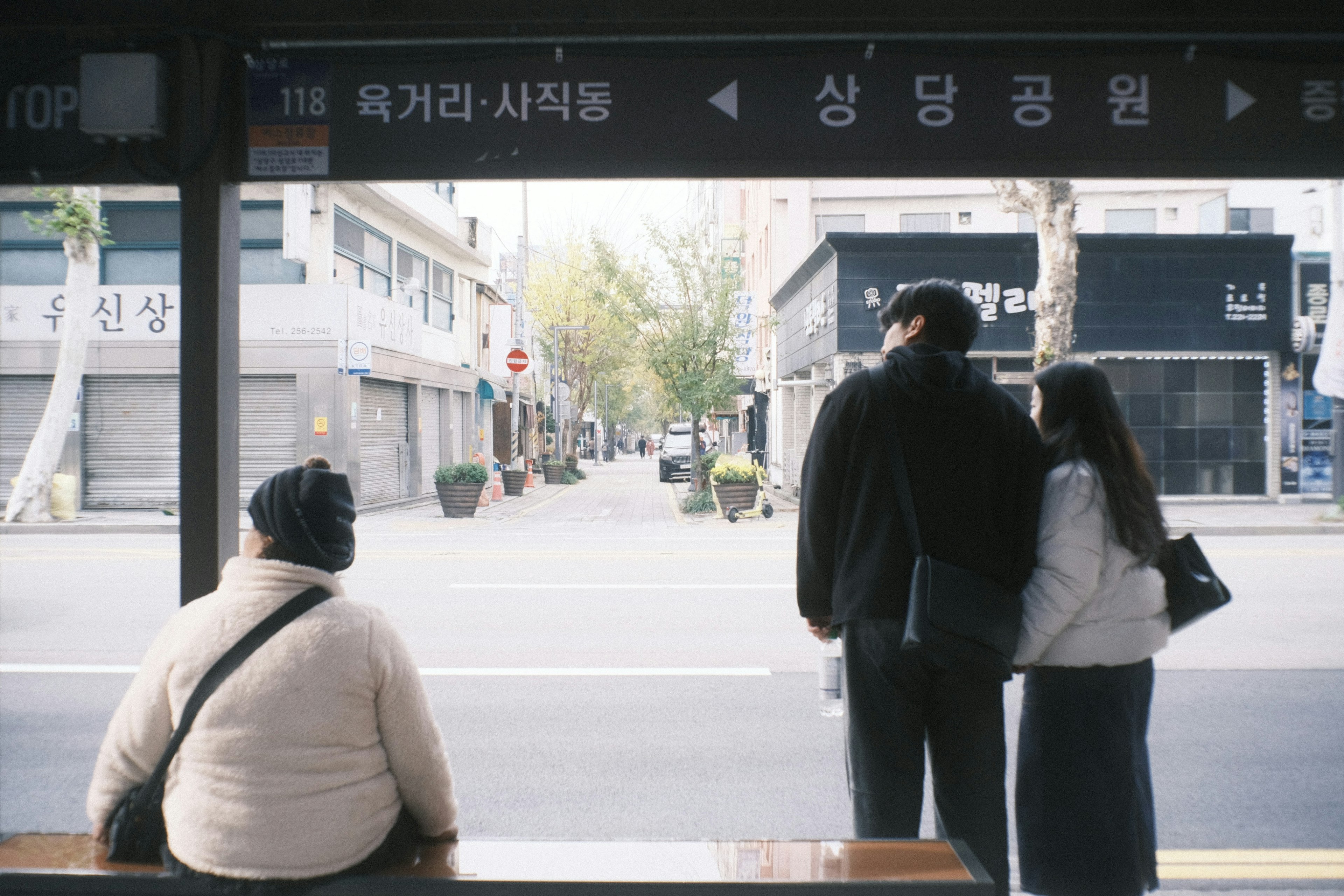 Personas esperando en una parada de autobús con paisaje urbano