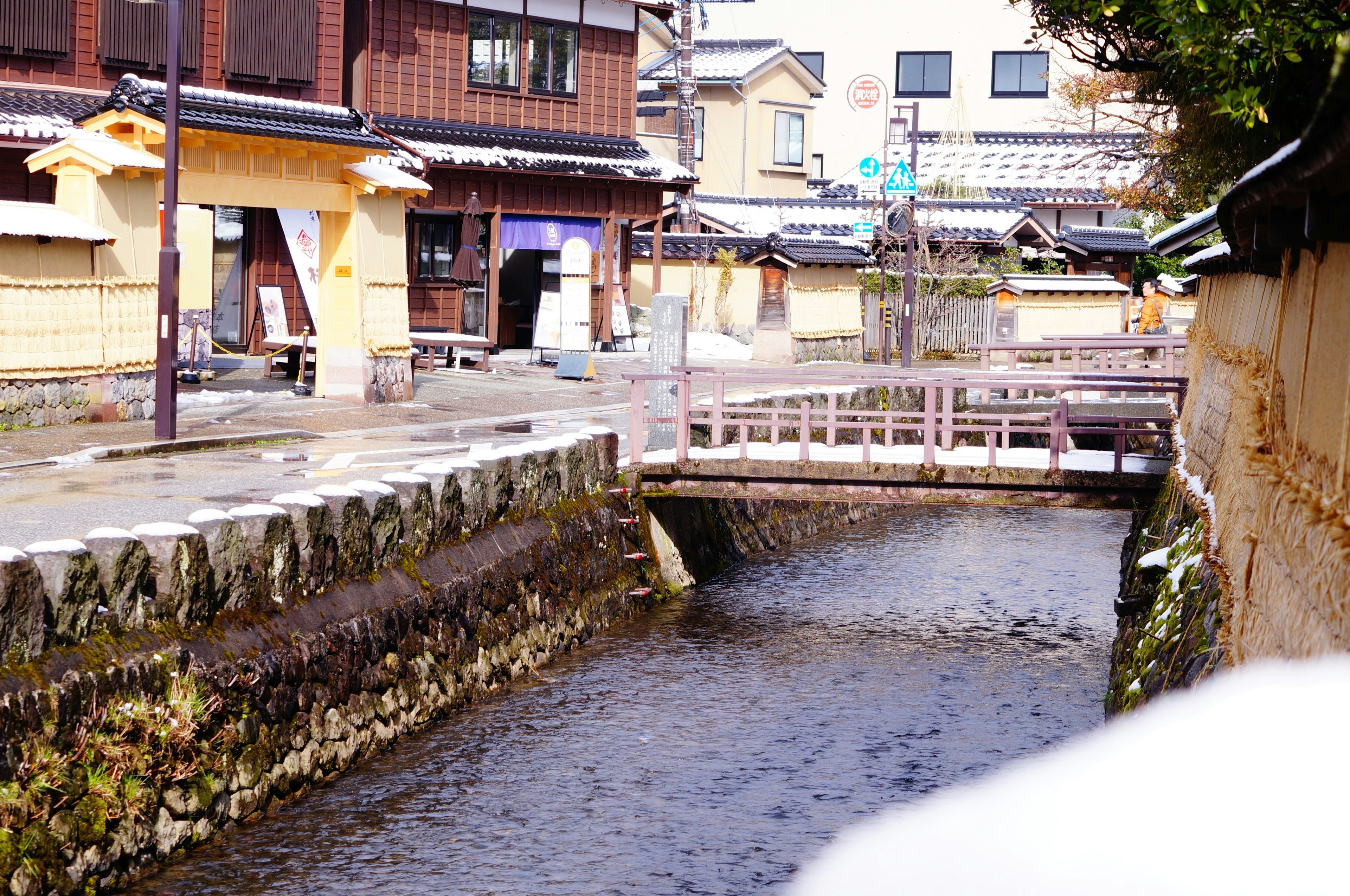 静かな川沿いの街並みと小さな橋が見える風景