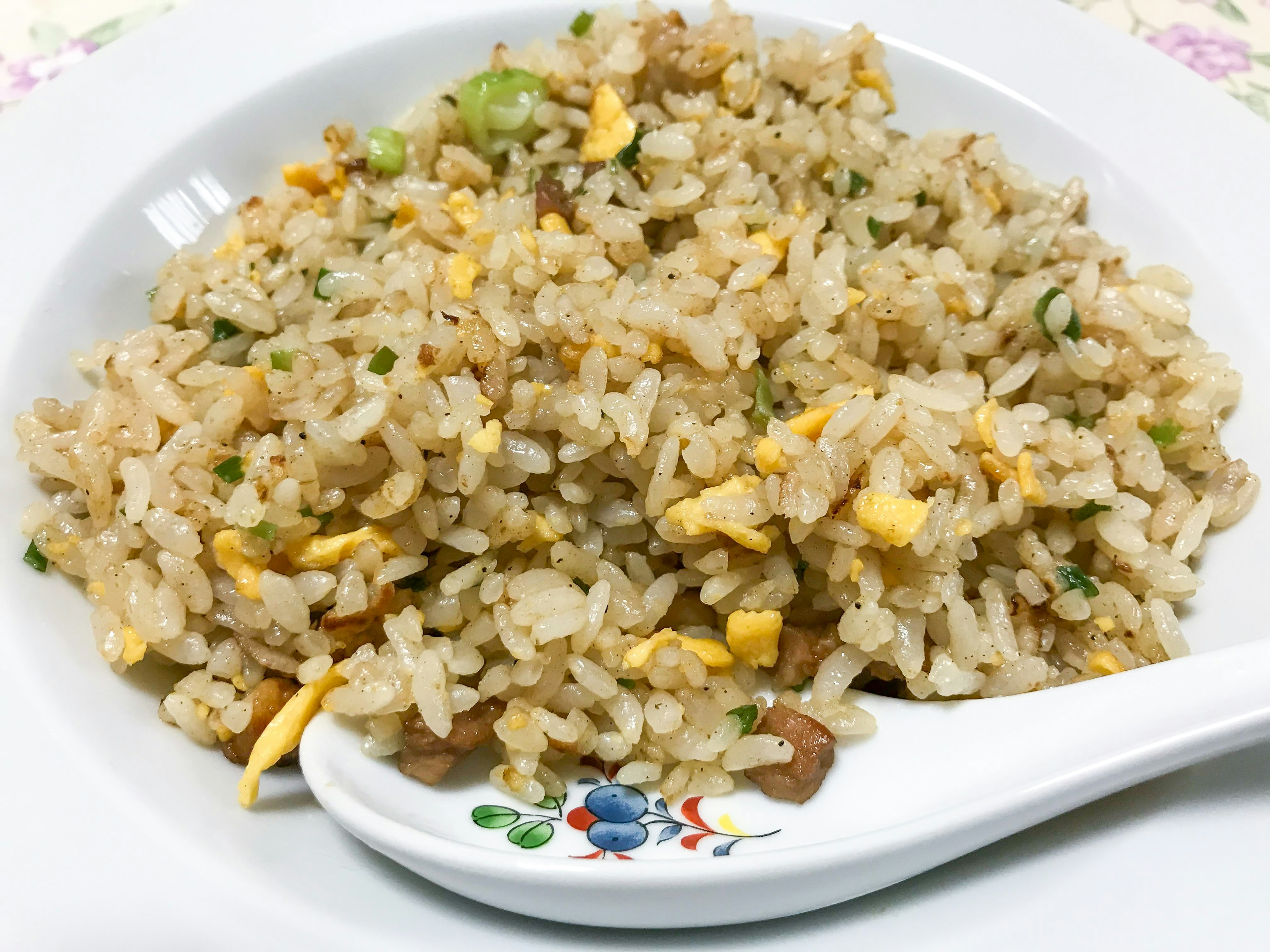 Fried rice served on a white plate with a spoon