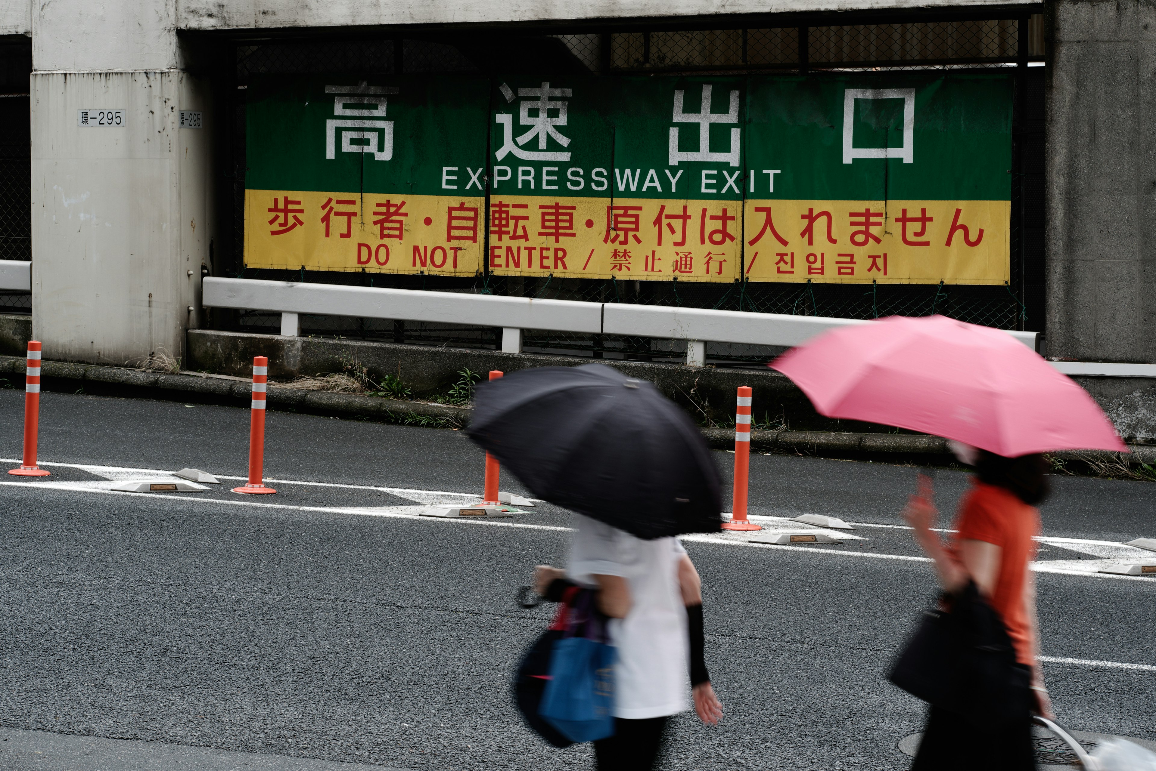 Expressway exit sign with pedestrians holding umbrellas