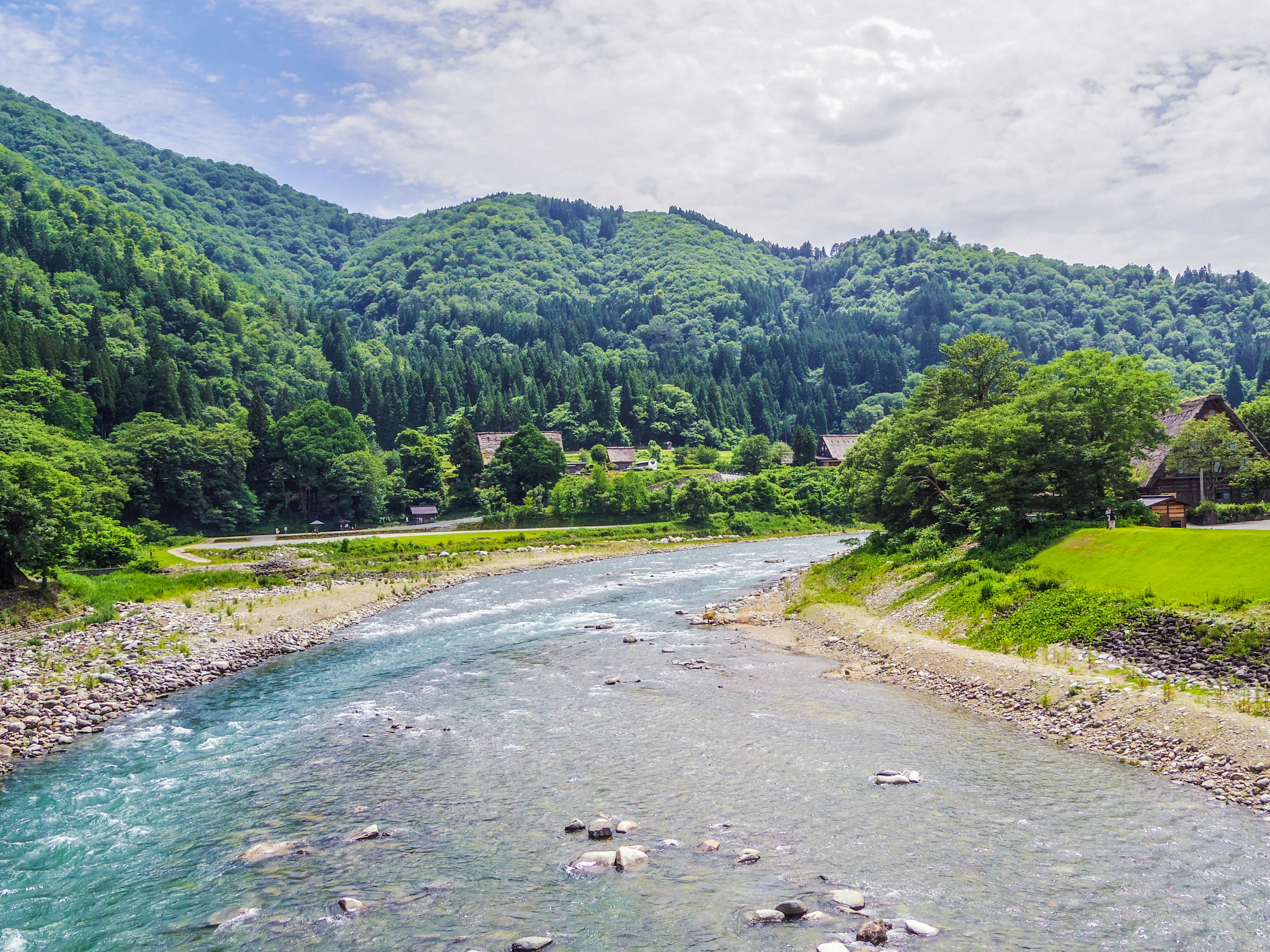 Vista panoramica di montagne verdi e di un fiume chiaro con case rurali