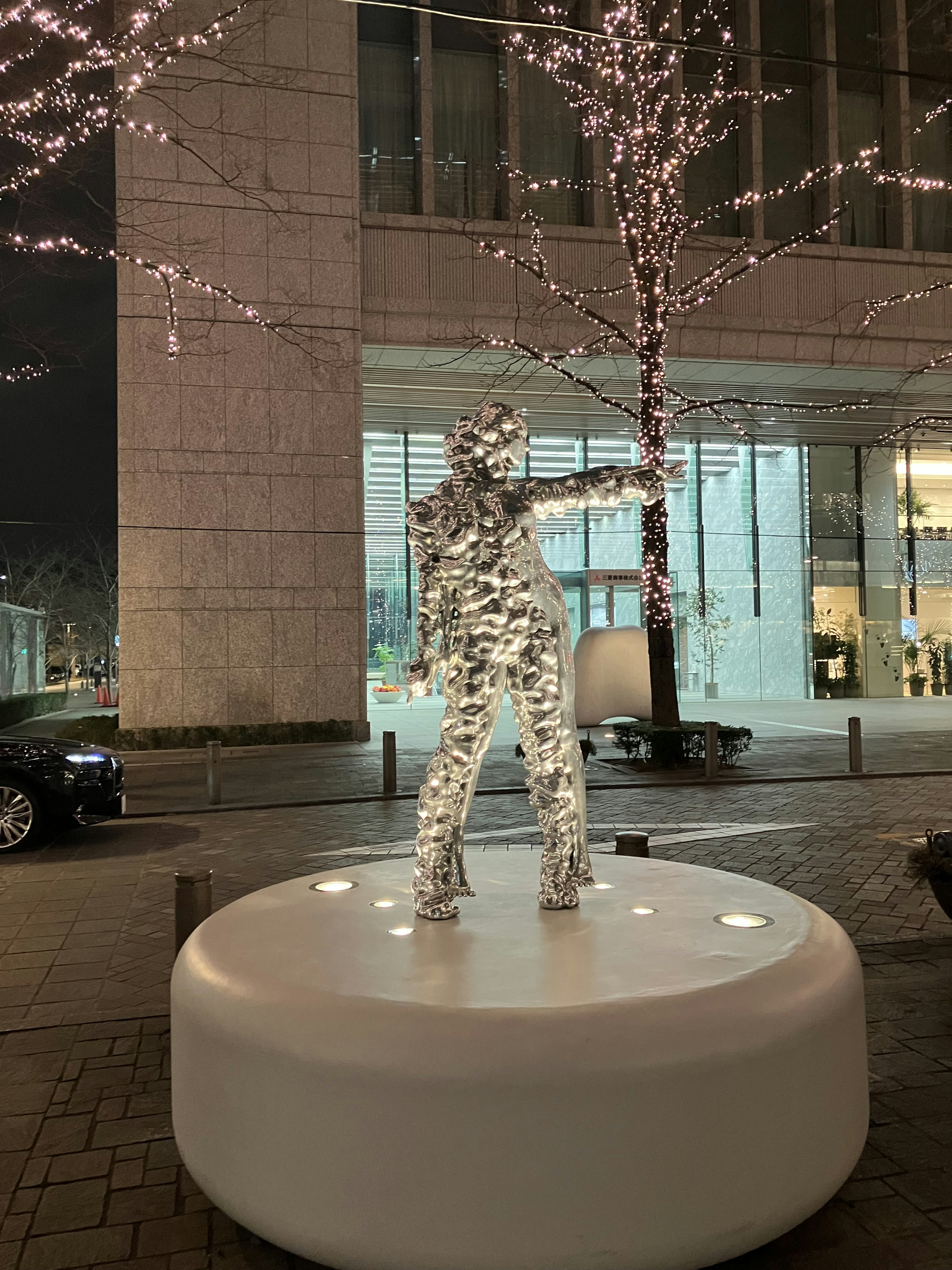 Une sculpture en forme humaine transparente éclairée la nuit dans une rue de la ville