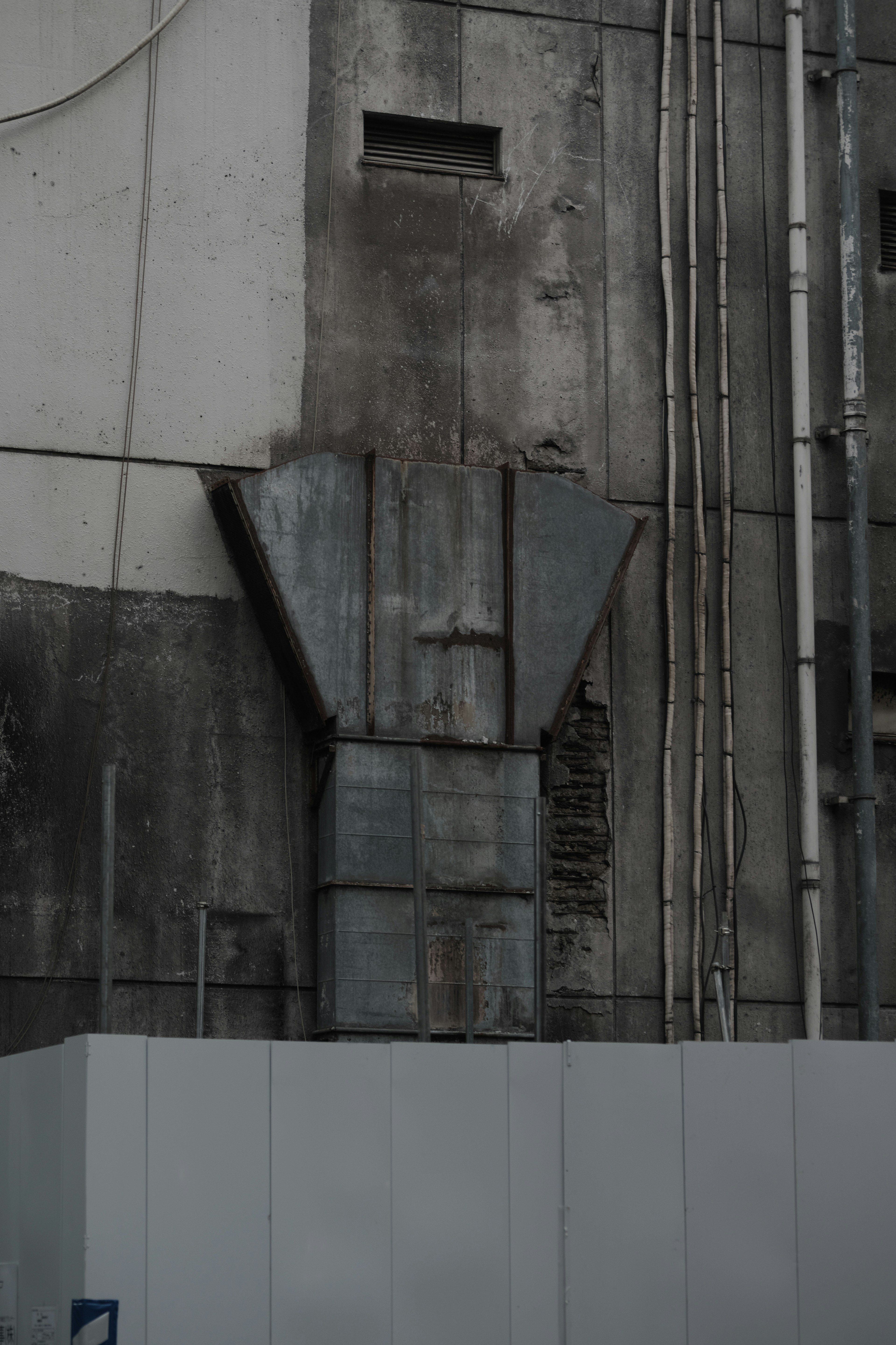 Ducte d'échappement en métal fixé à un mur en béton usé avec des tuyaux visibles