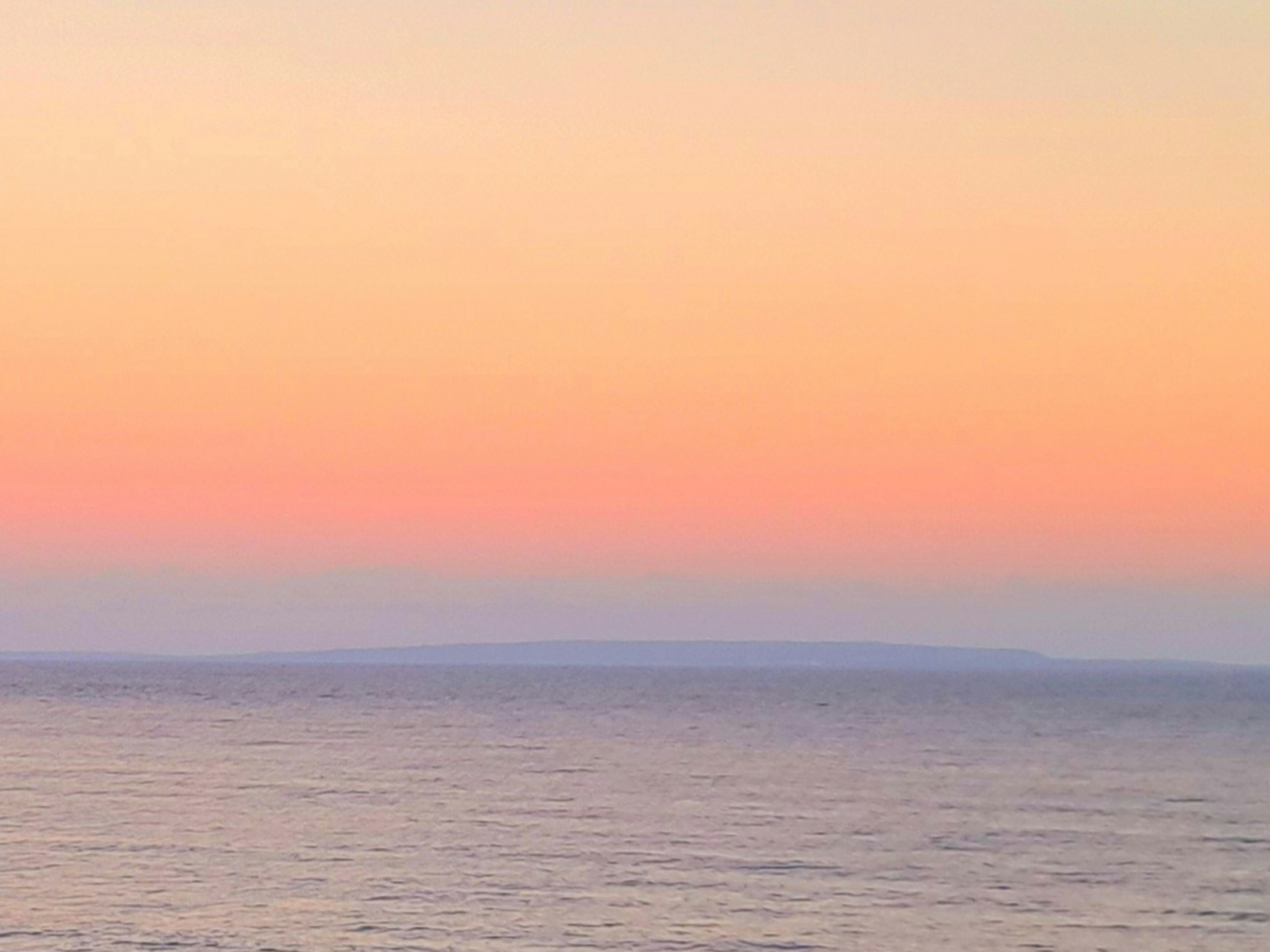 Ruhiges Meer mit einem sanften rosa Himmel