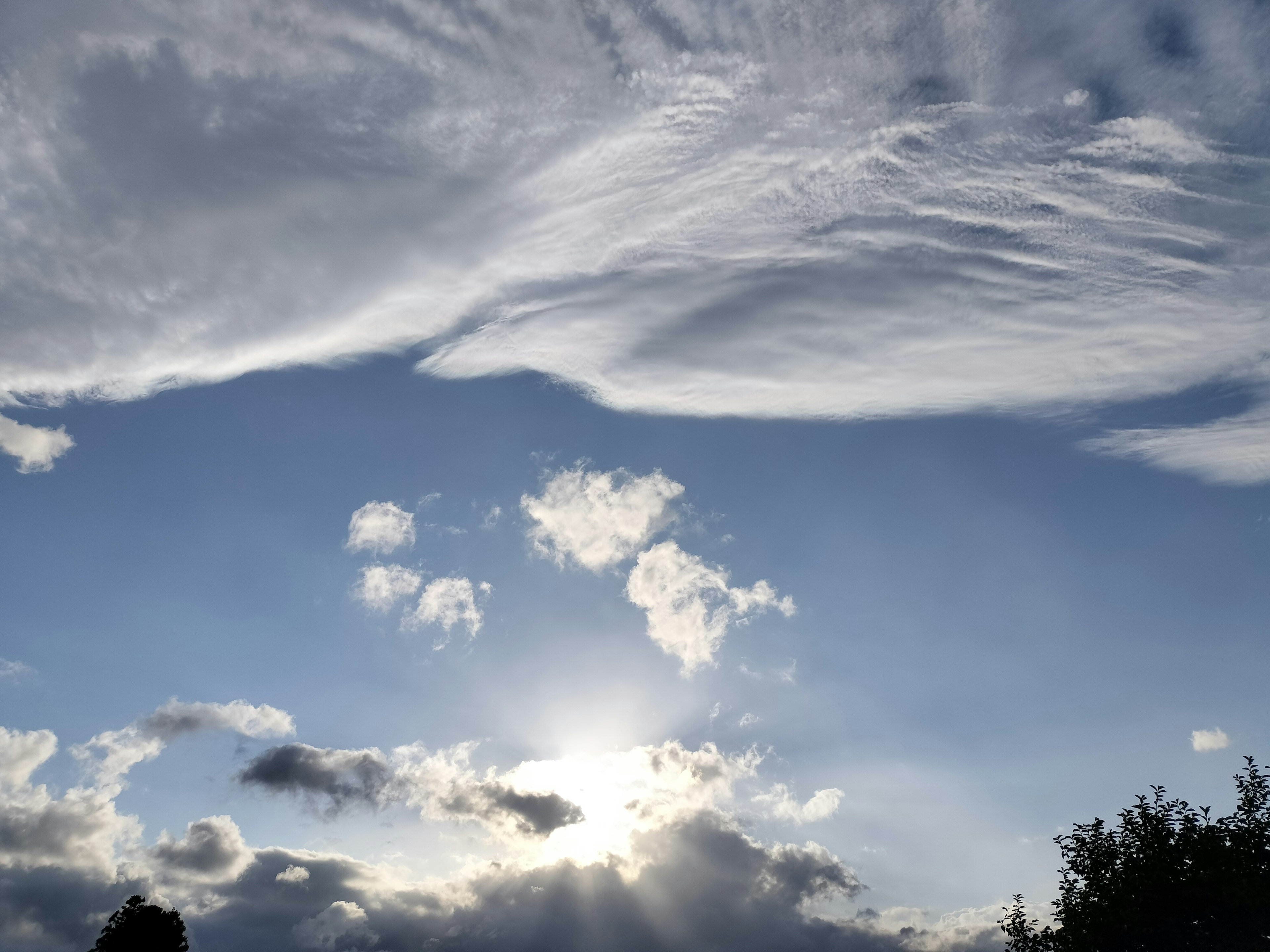 青空と雲が広がる風景で太陽が雲の間から差し込む