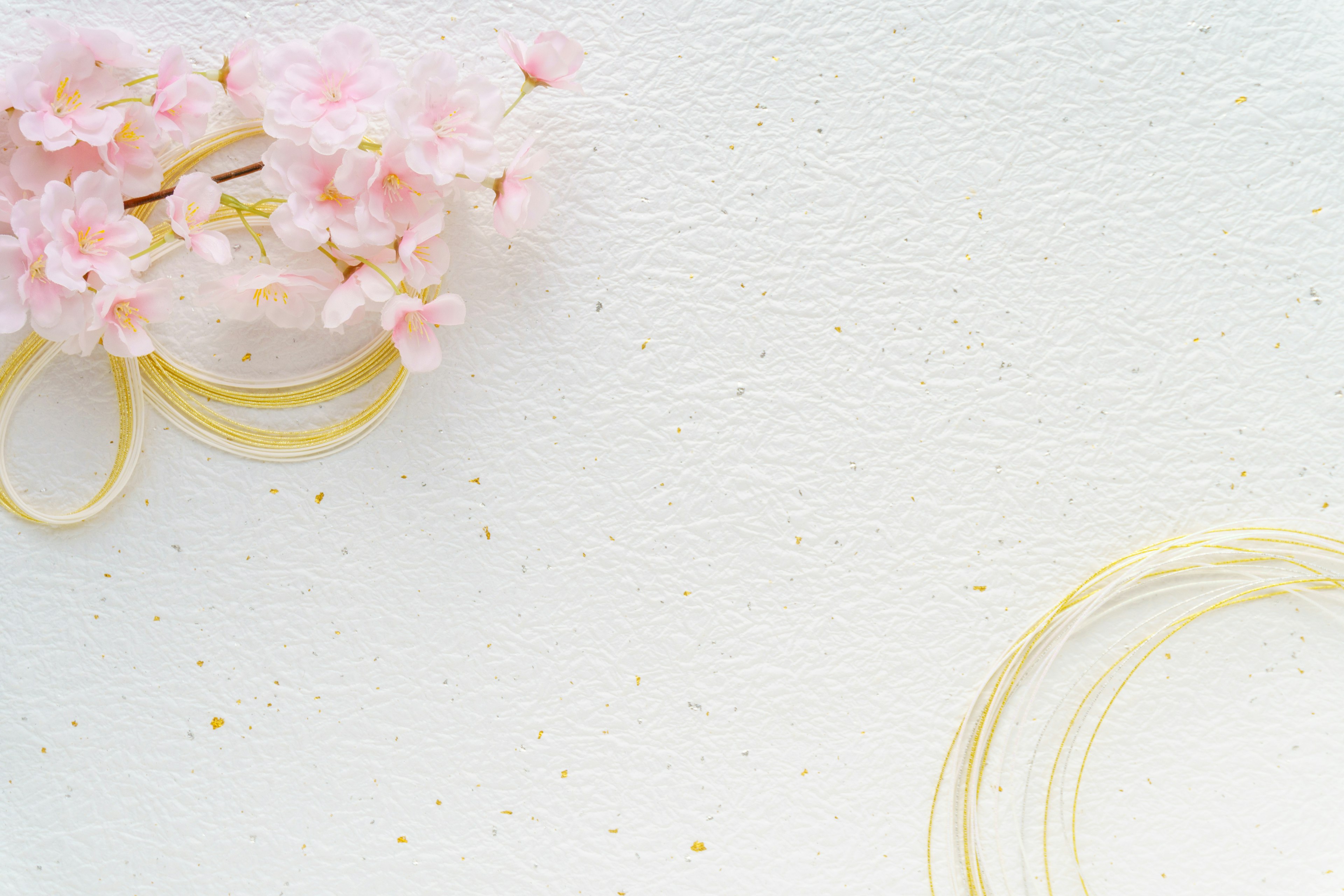 Delicate pink flowers and yellow ribbons arranged on a white background