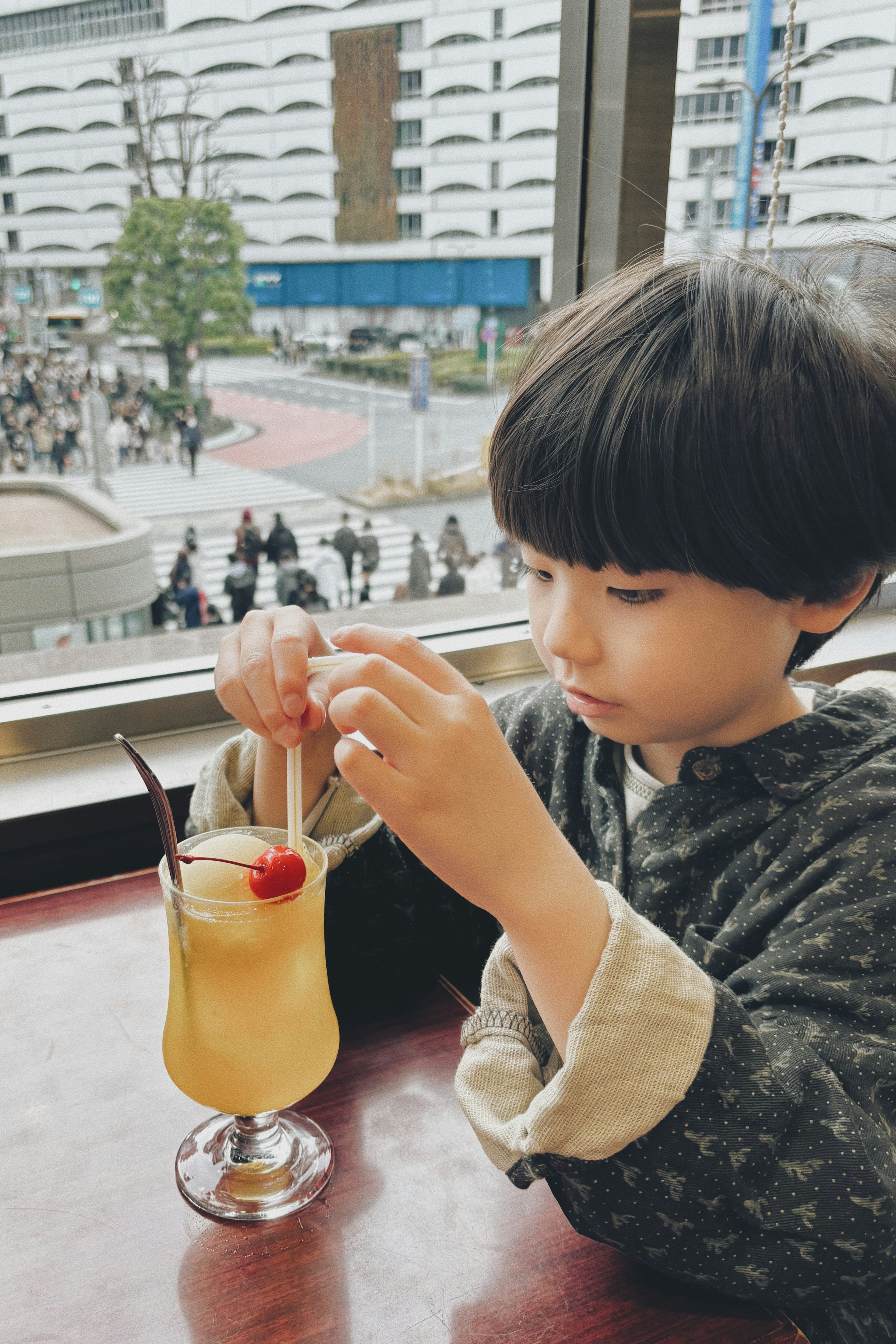 Child enjoying a drink by the window with fruit garnish