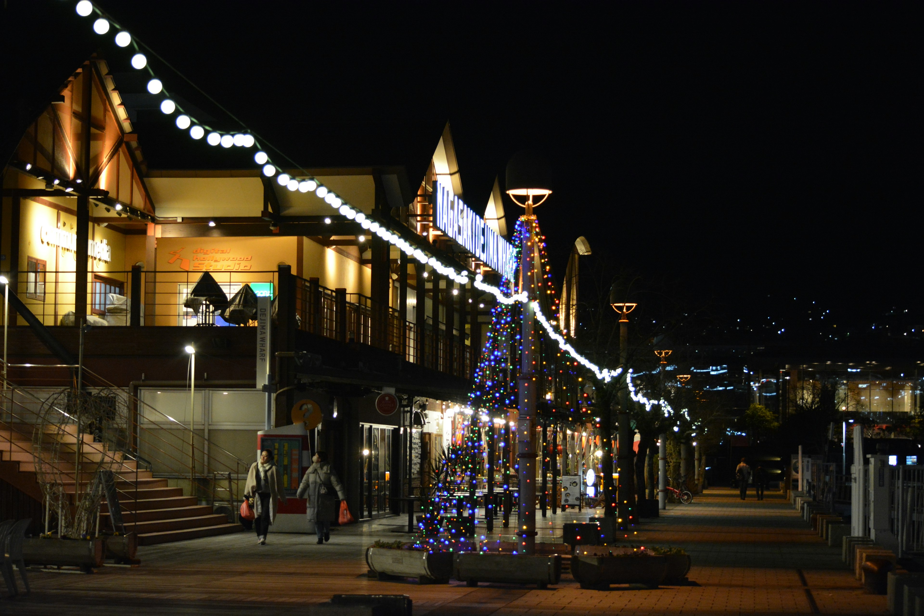 Escena nocturna de la calle con un árbol de Navidad iluminado y luces festivas