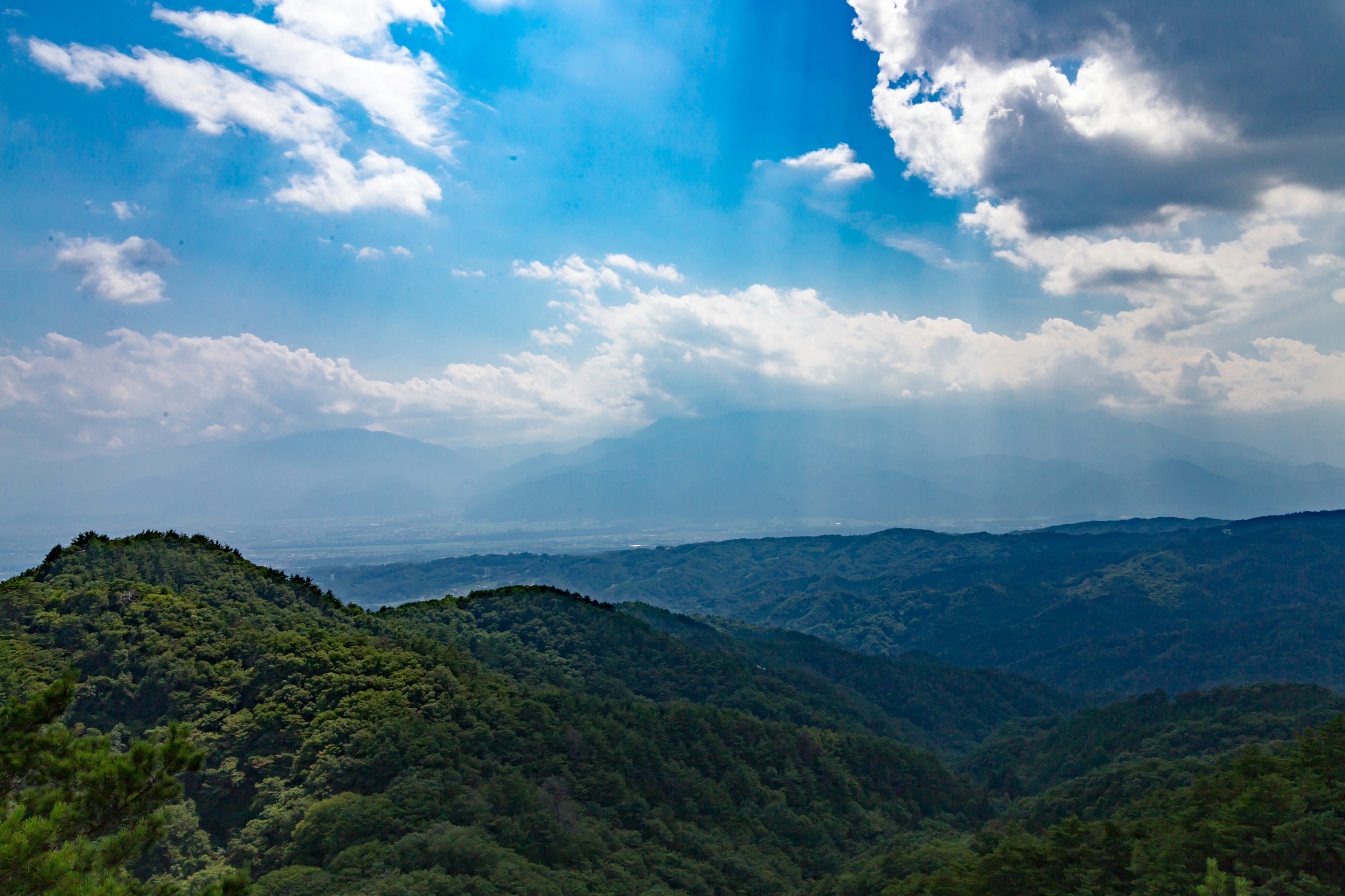 Paisaje montañoso con cielo azul y nubes colinas y valles verdes