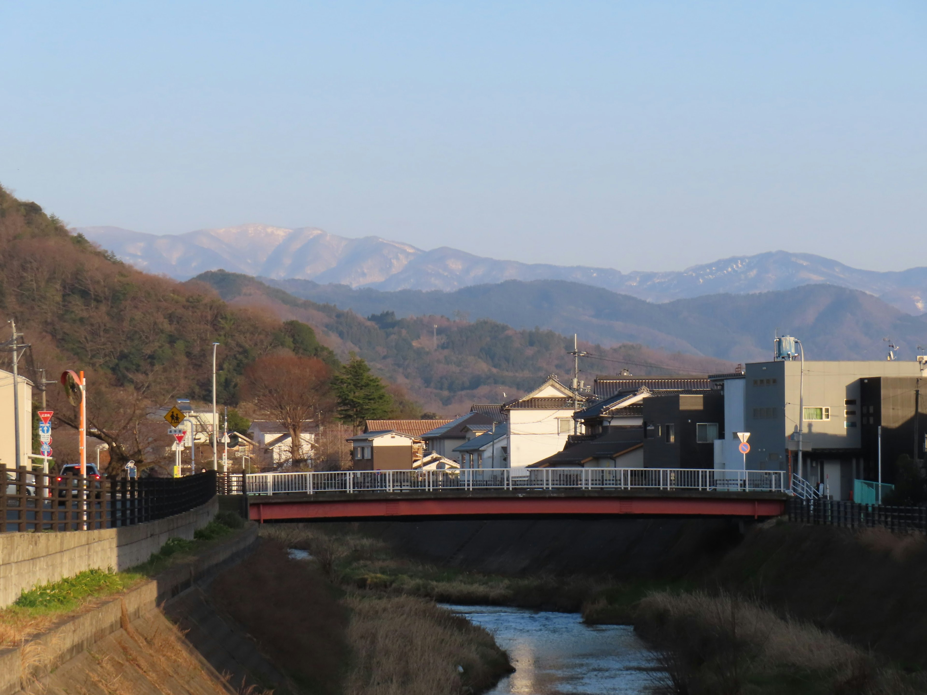 Vista panoramica di un fiume e di un ponte rosso con montagne sullo sfondo