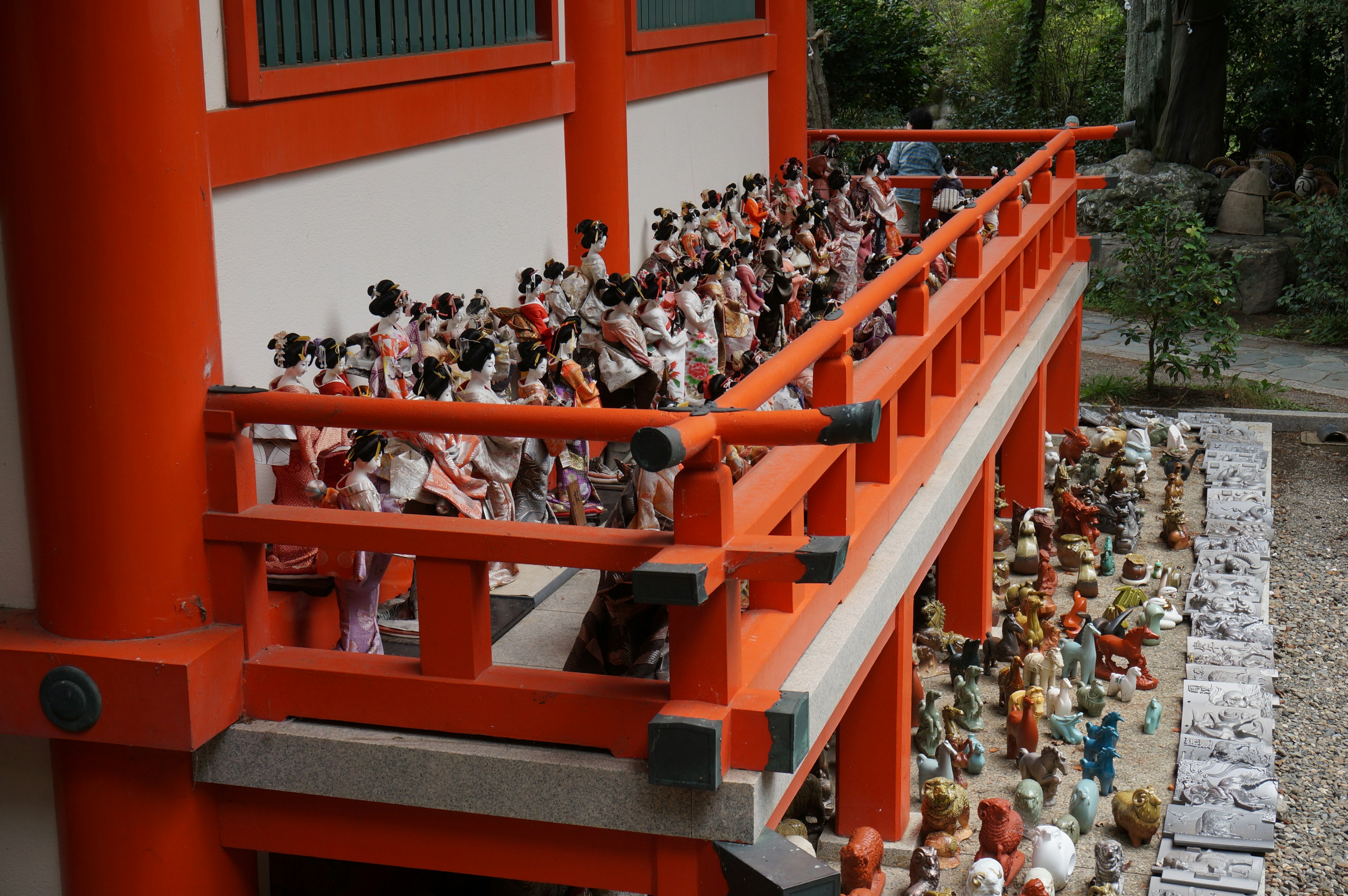 Many dolls lined up on the balcony of a red building