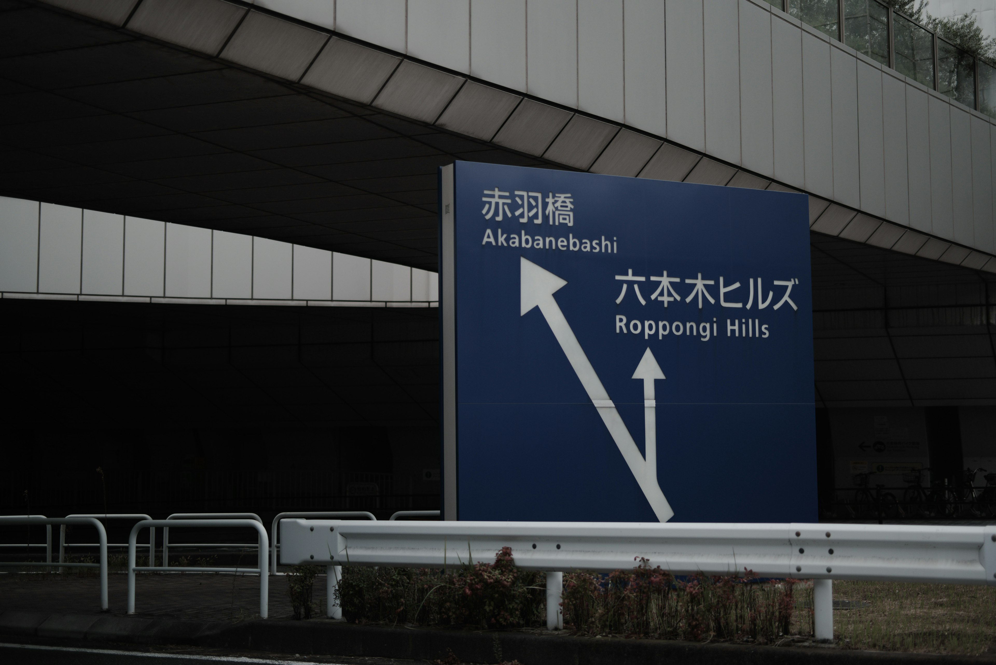 Cartel azul que indica direcciones hacia Akabane Bridge y Roppongi Hills