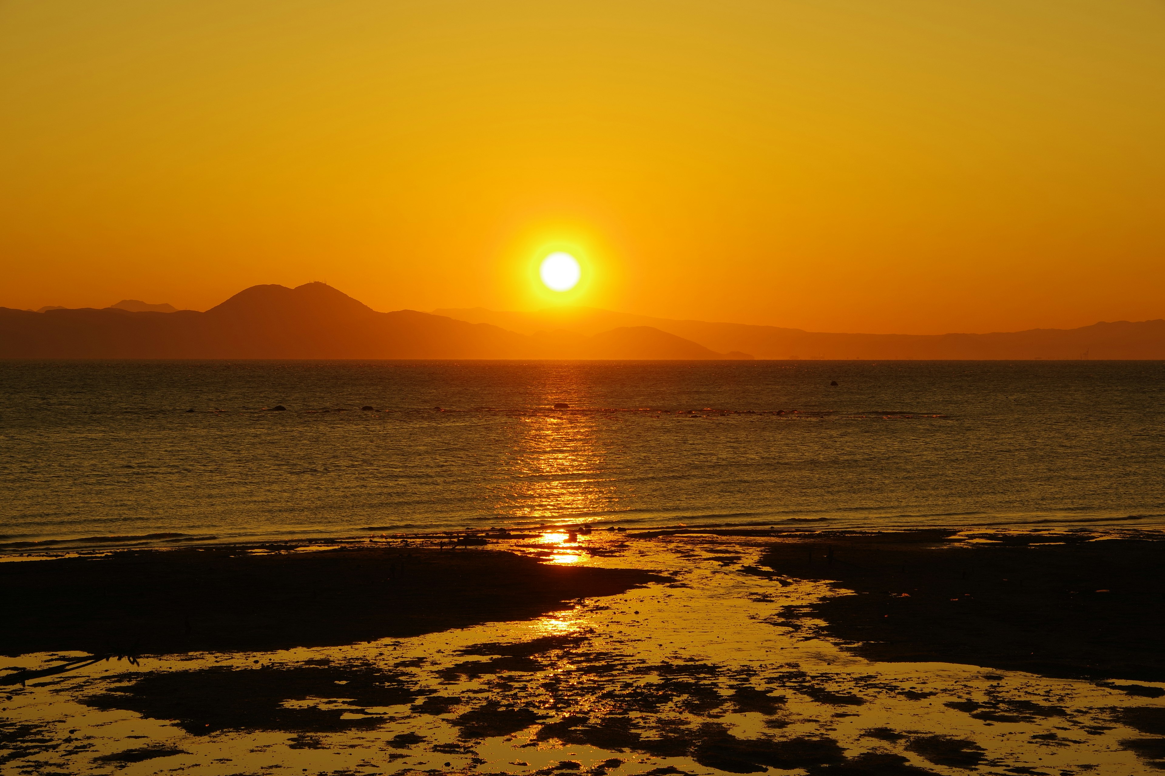 Beautiful sunset over the ocean with a vibrant orange sky and reflective water