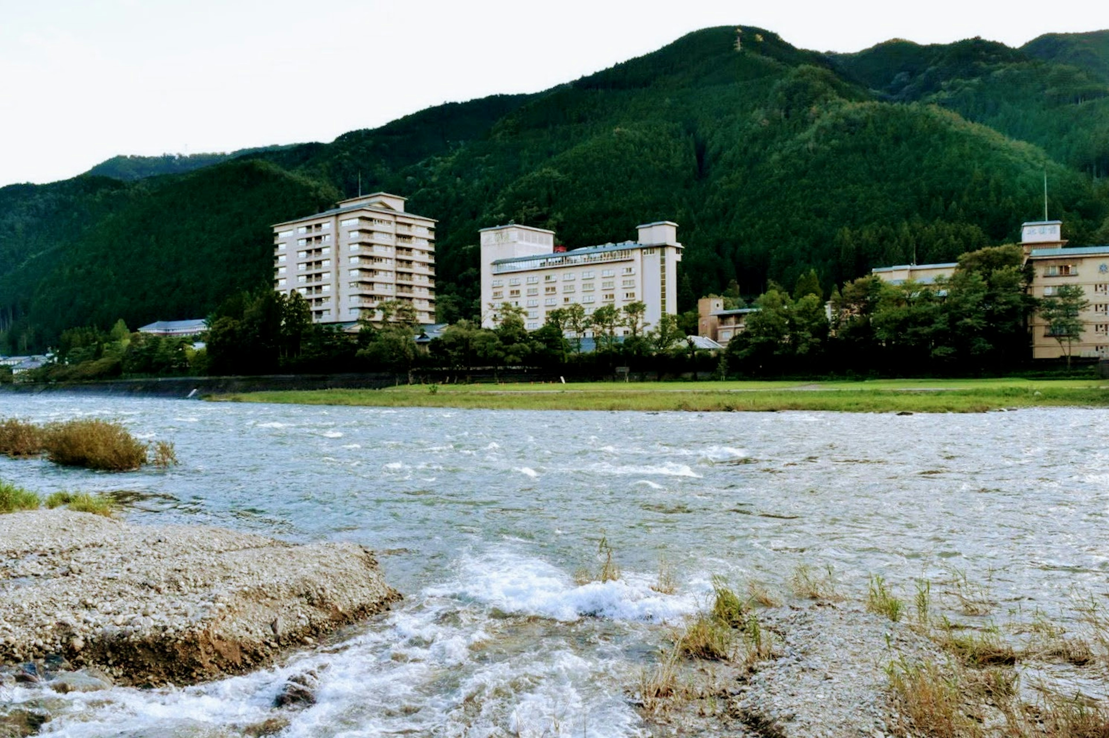 Vista escénica de edificios a lo largo de un río con montañas al fondo