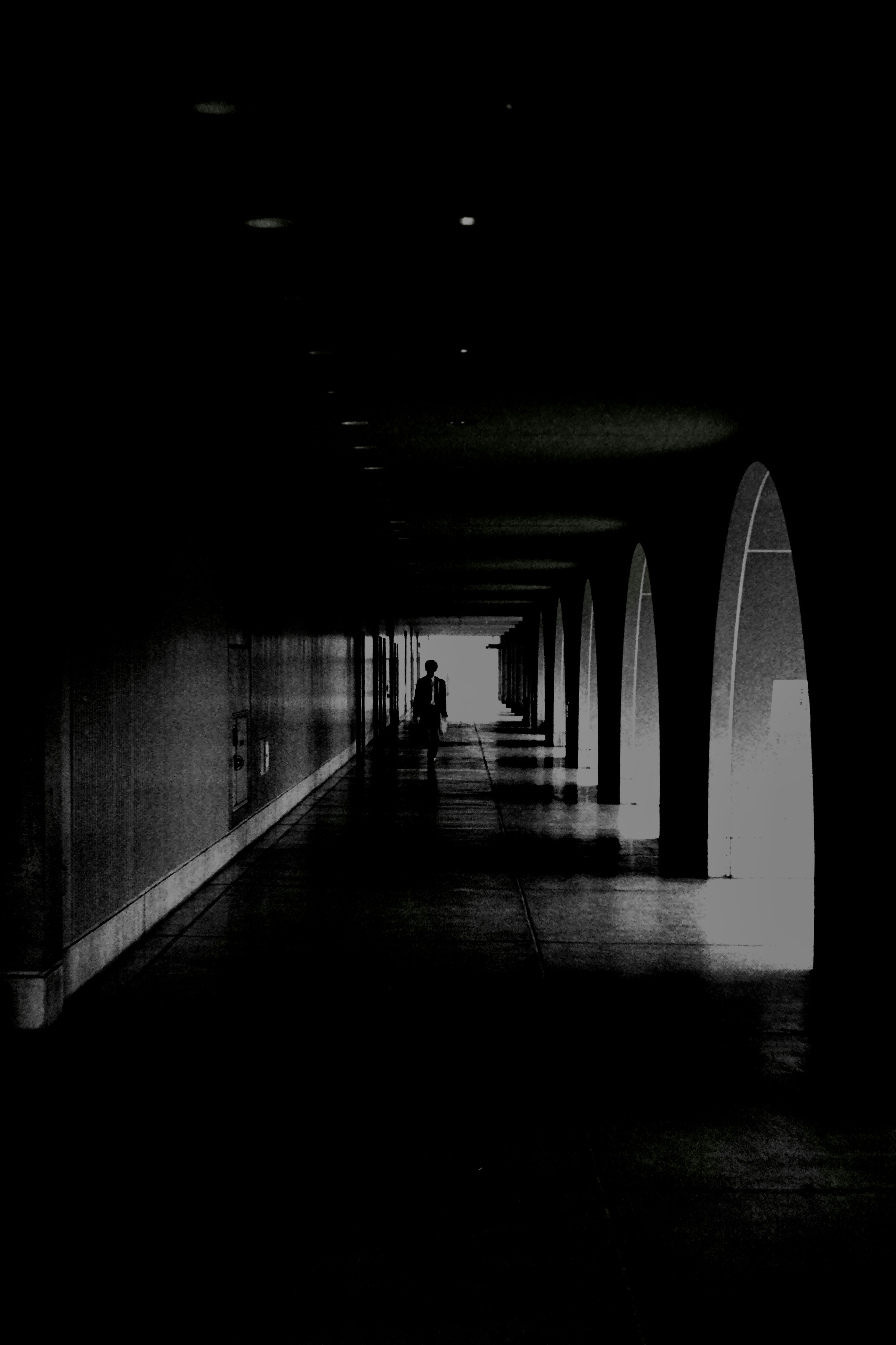 Dark corridor with a figure standing and arched openings