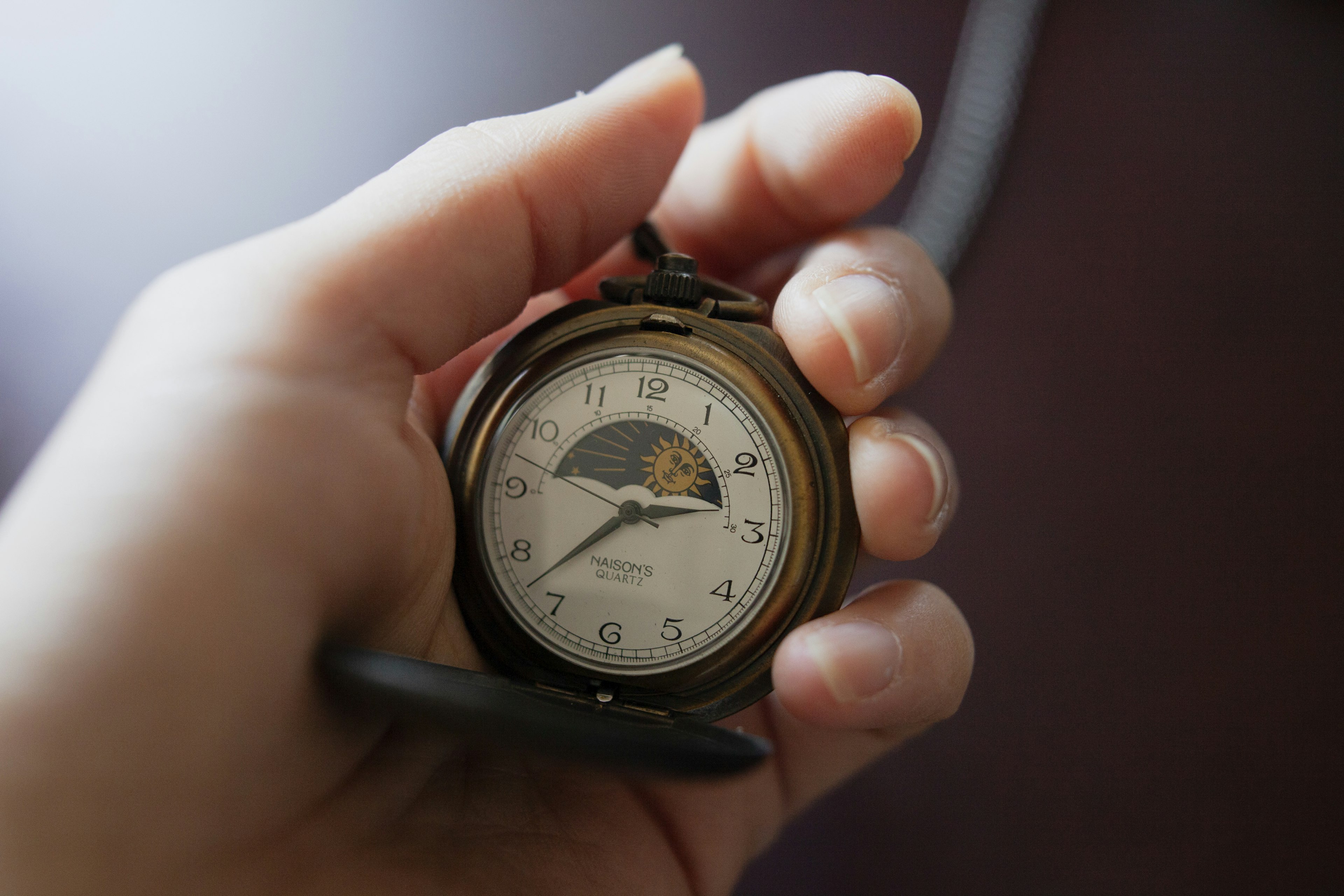 A classic pocket watch held in a hand with a simple design