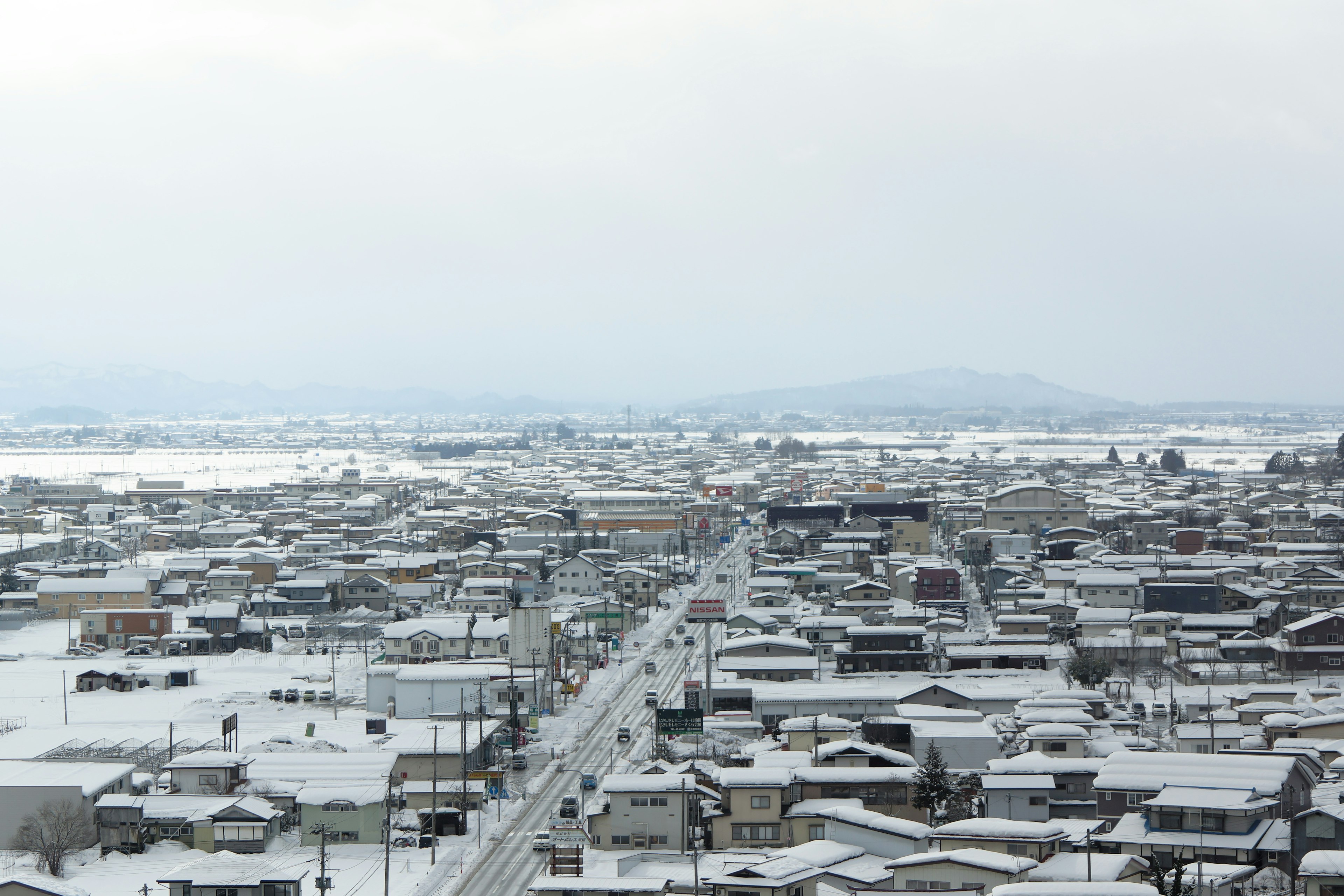 Vista de una ciudad cubierta de nieve con montañas a lo lejos