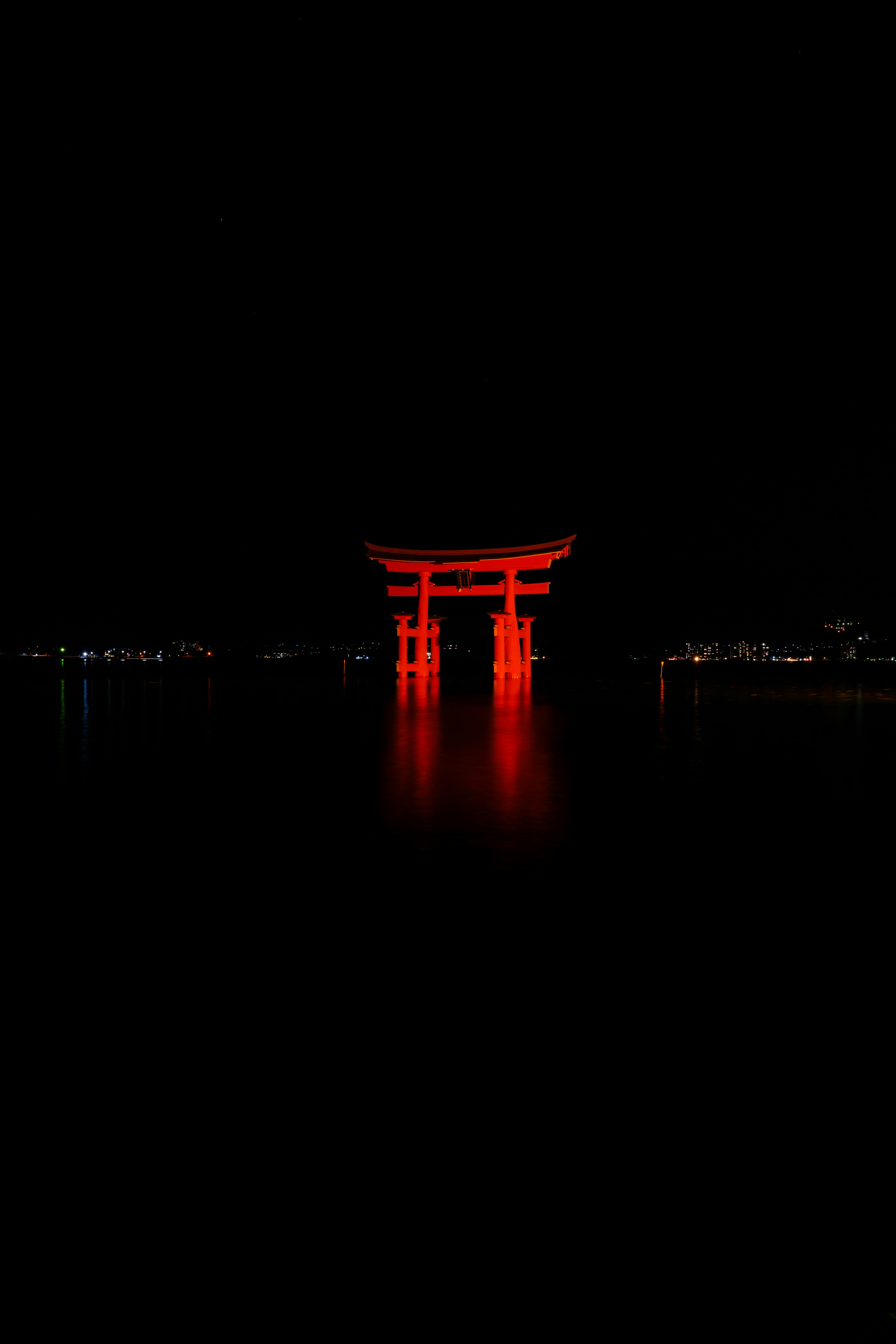 Wunderschön beleuchtetes rotes Torii vor dunklem Hintergrund