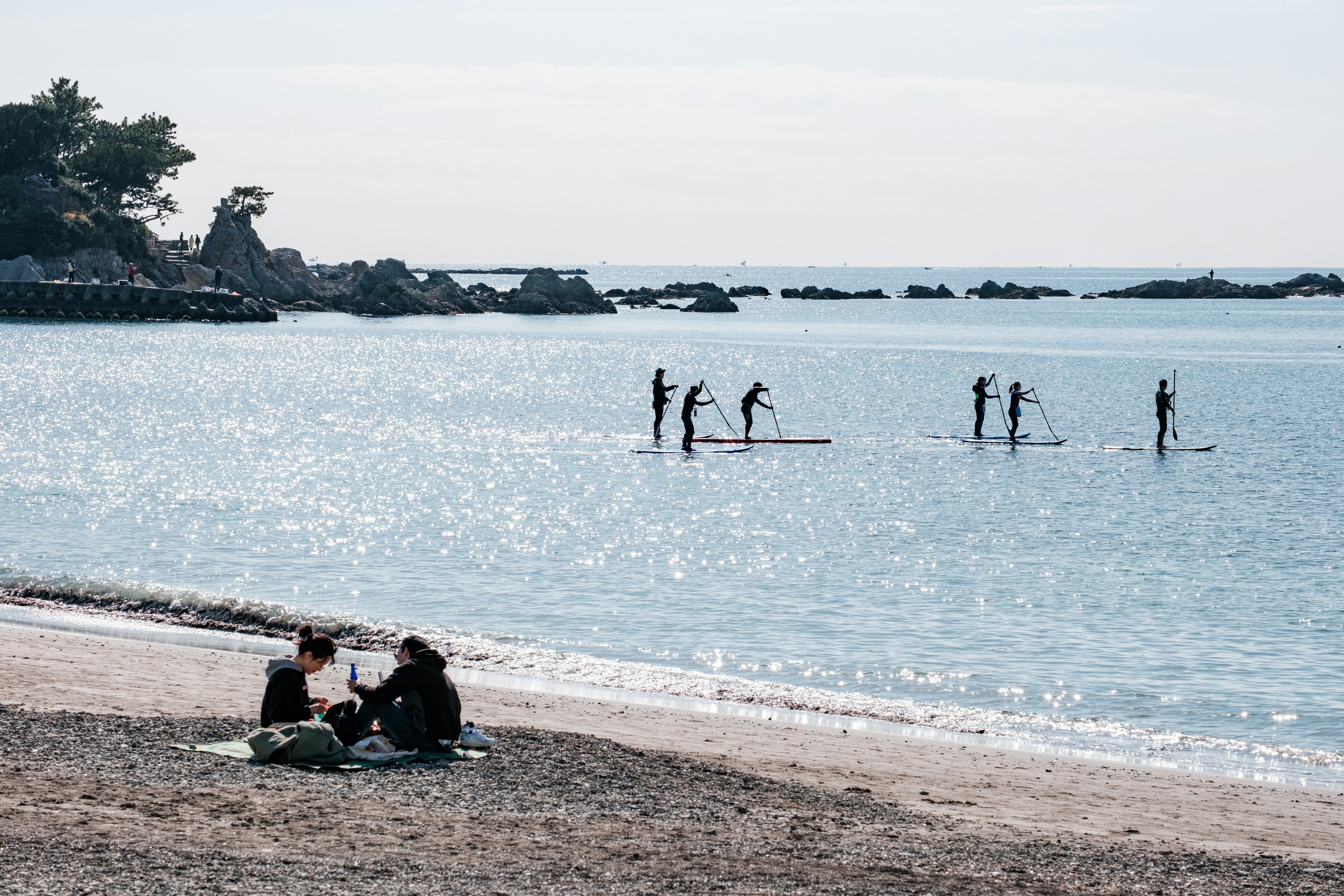 Personas disfrutando de una playa tranquila con paddle surf