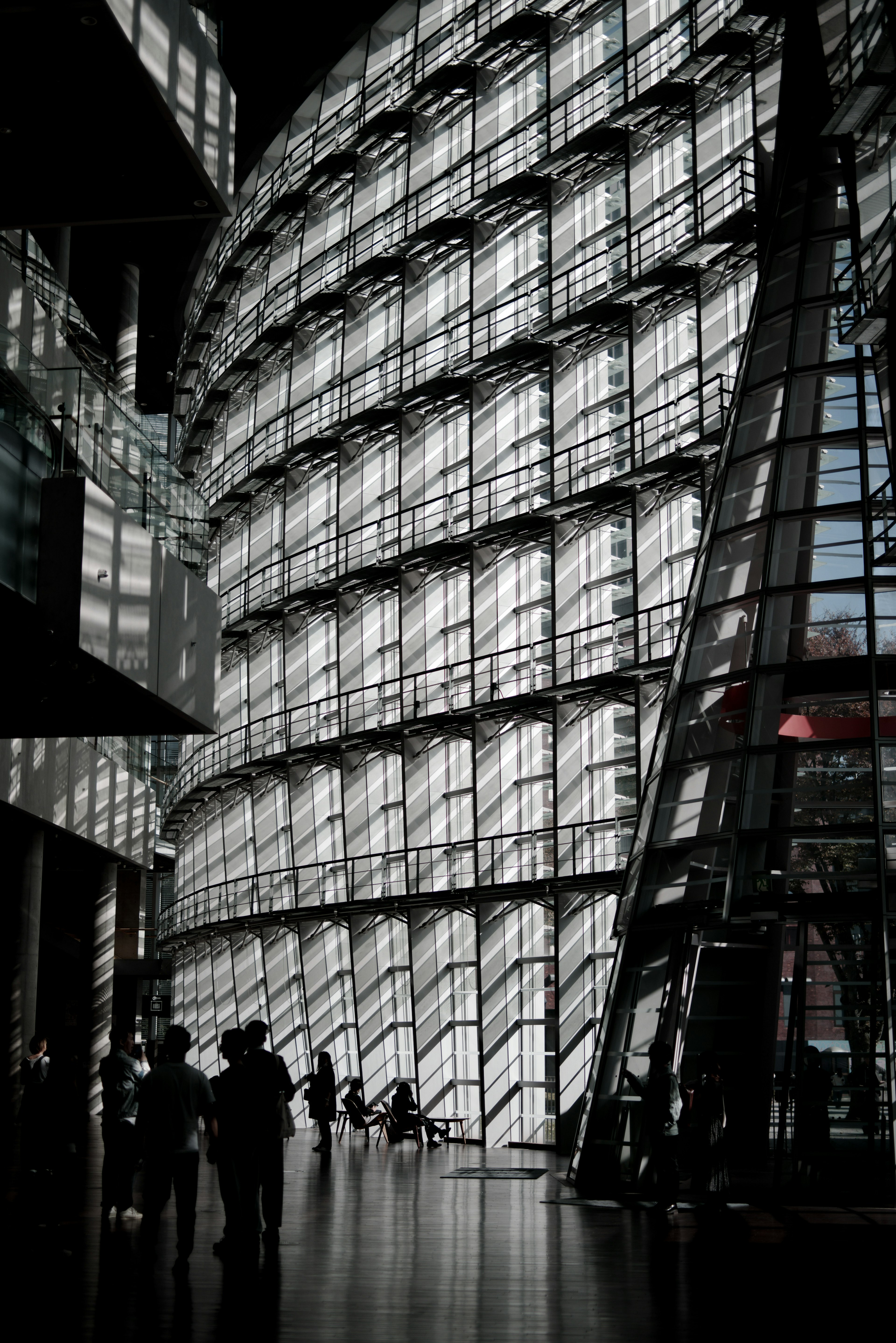 Interno di un edificio moderno con grandi pareti di vetro e figure in silhouette