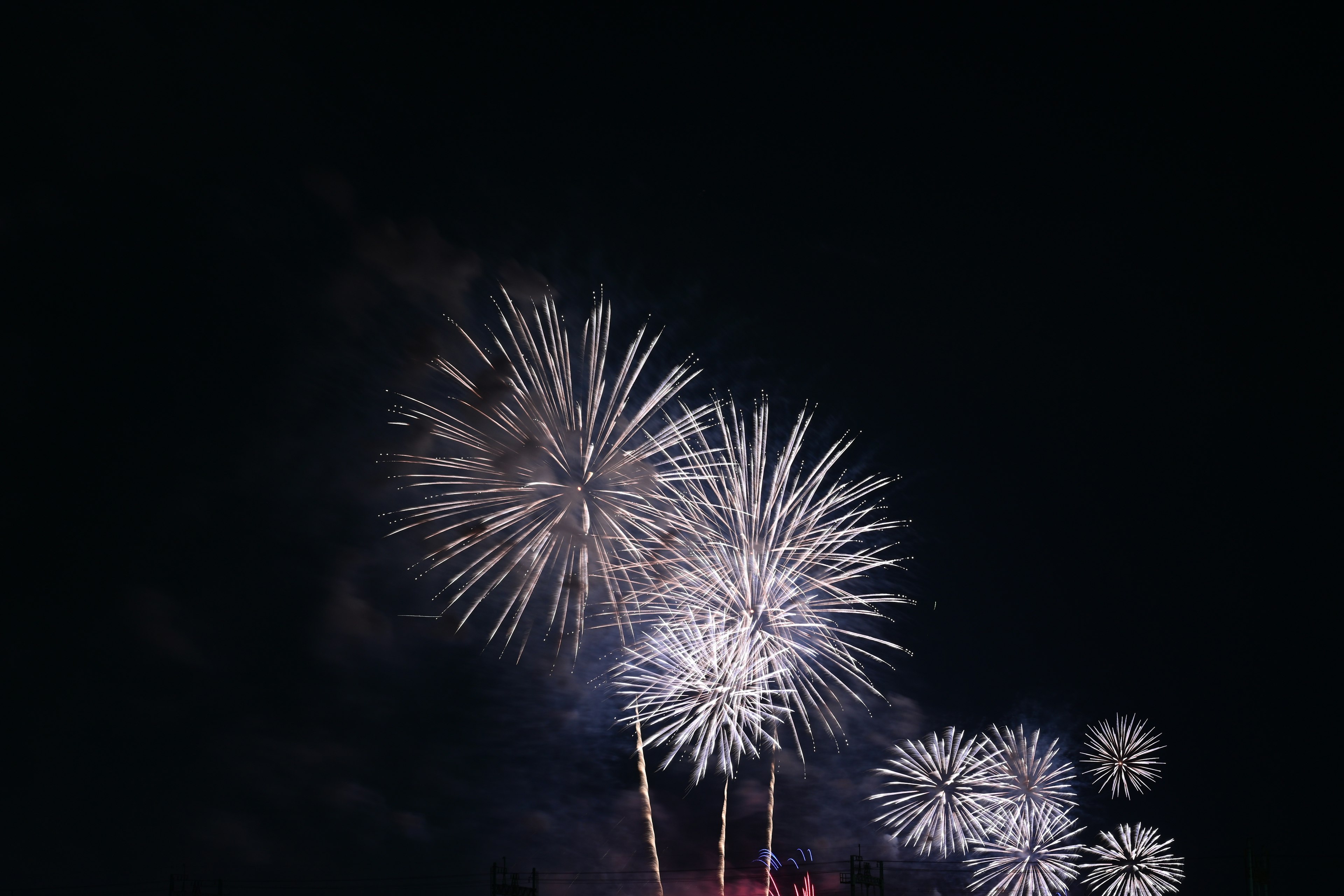 Un groupe de feux d'artifice blancs brillants dans le ciel nocturne