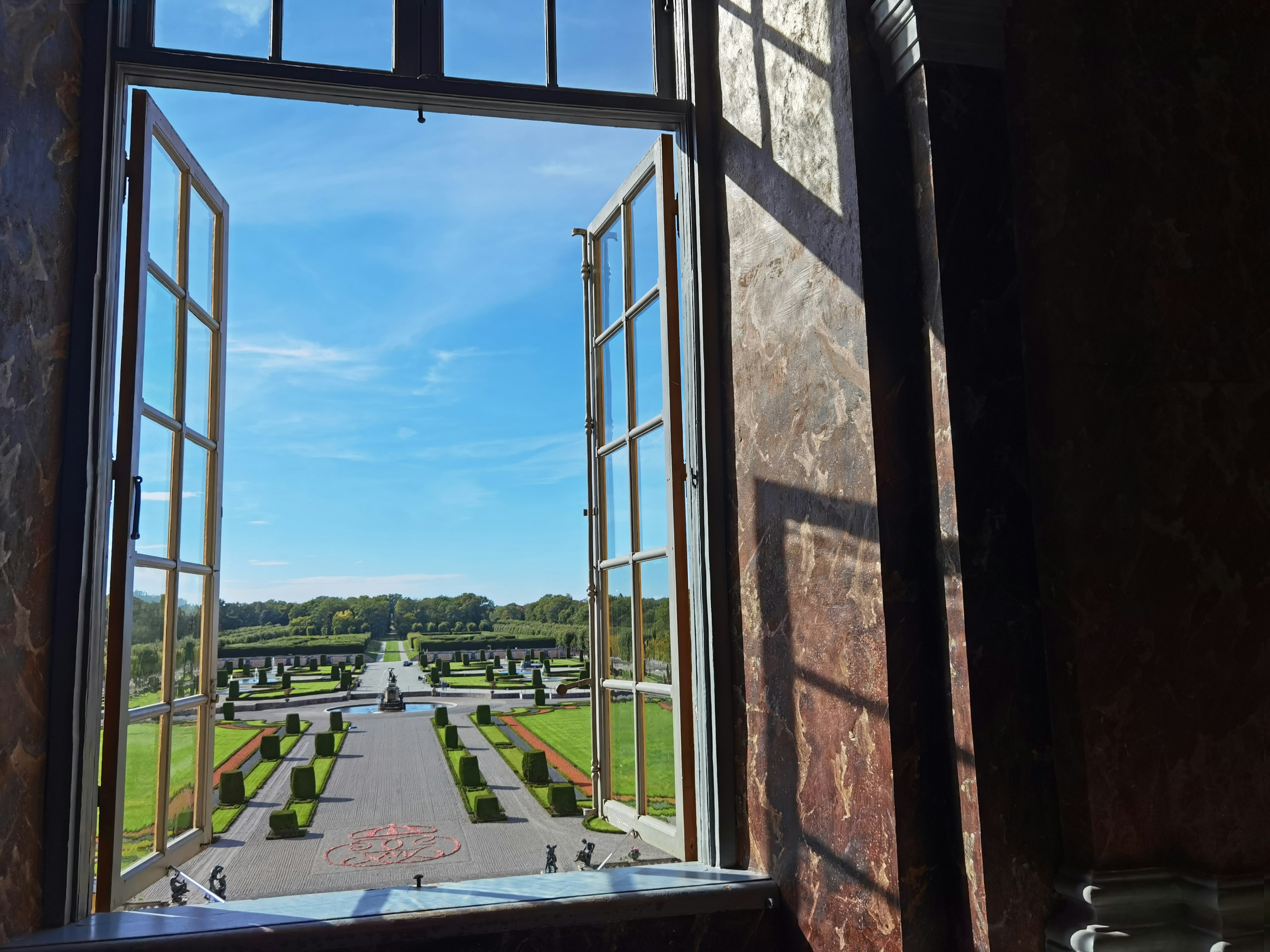 Vista de un hermoso jardín y cielo azul desde una ventana abierta