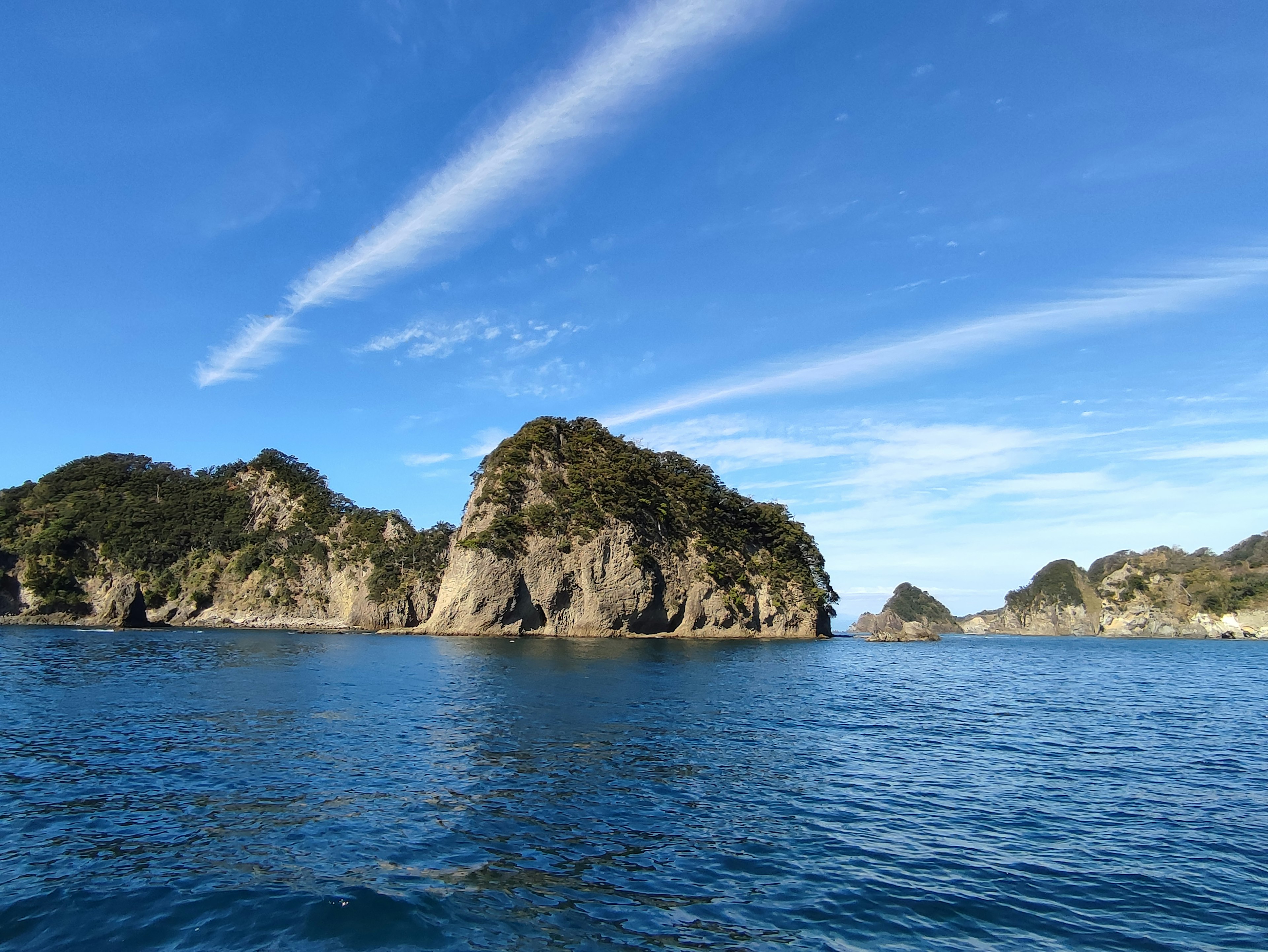 Scenic view of blue ocean and rocky islands under a clear sky