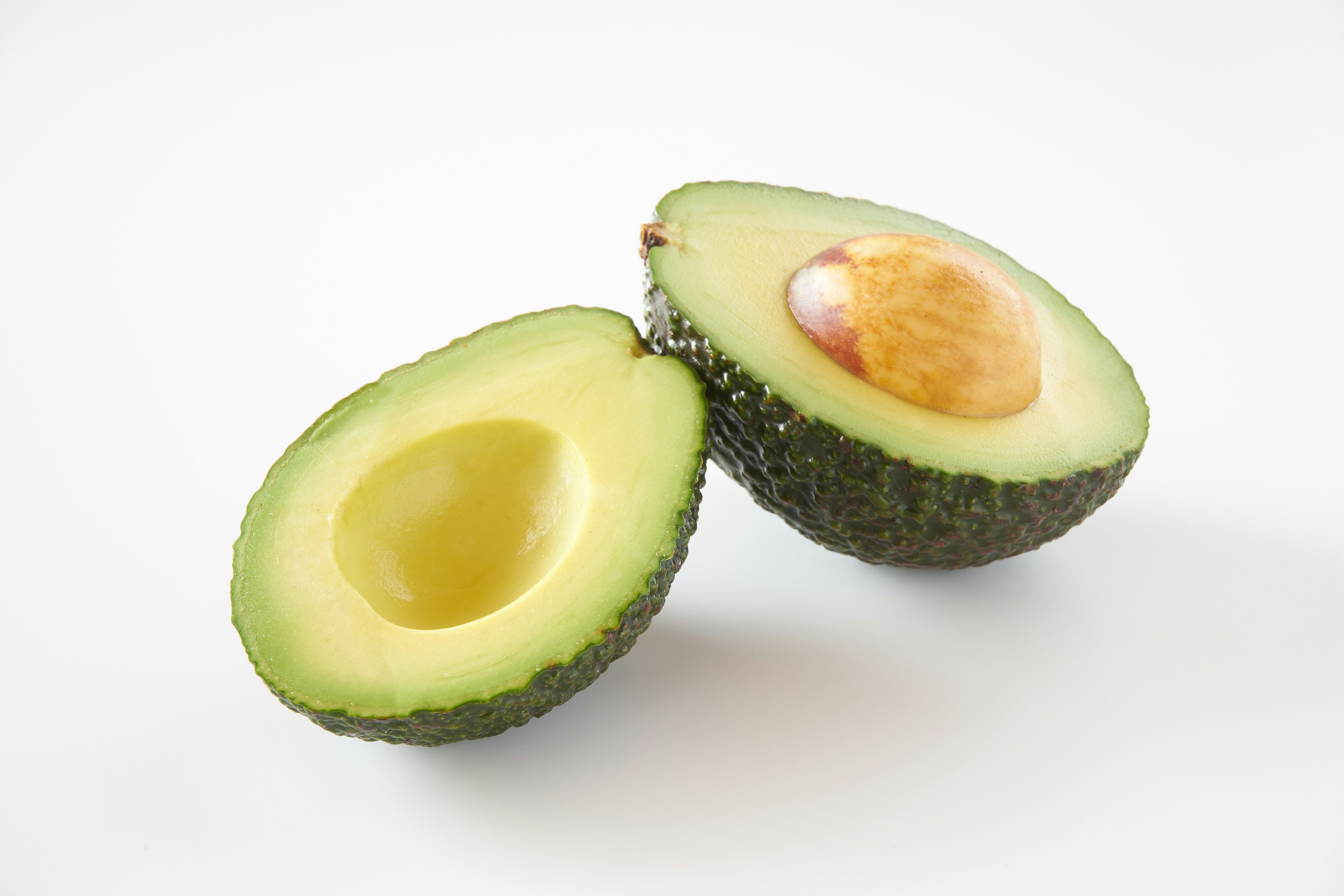 Halved avocado showcasing green flesh and seed