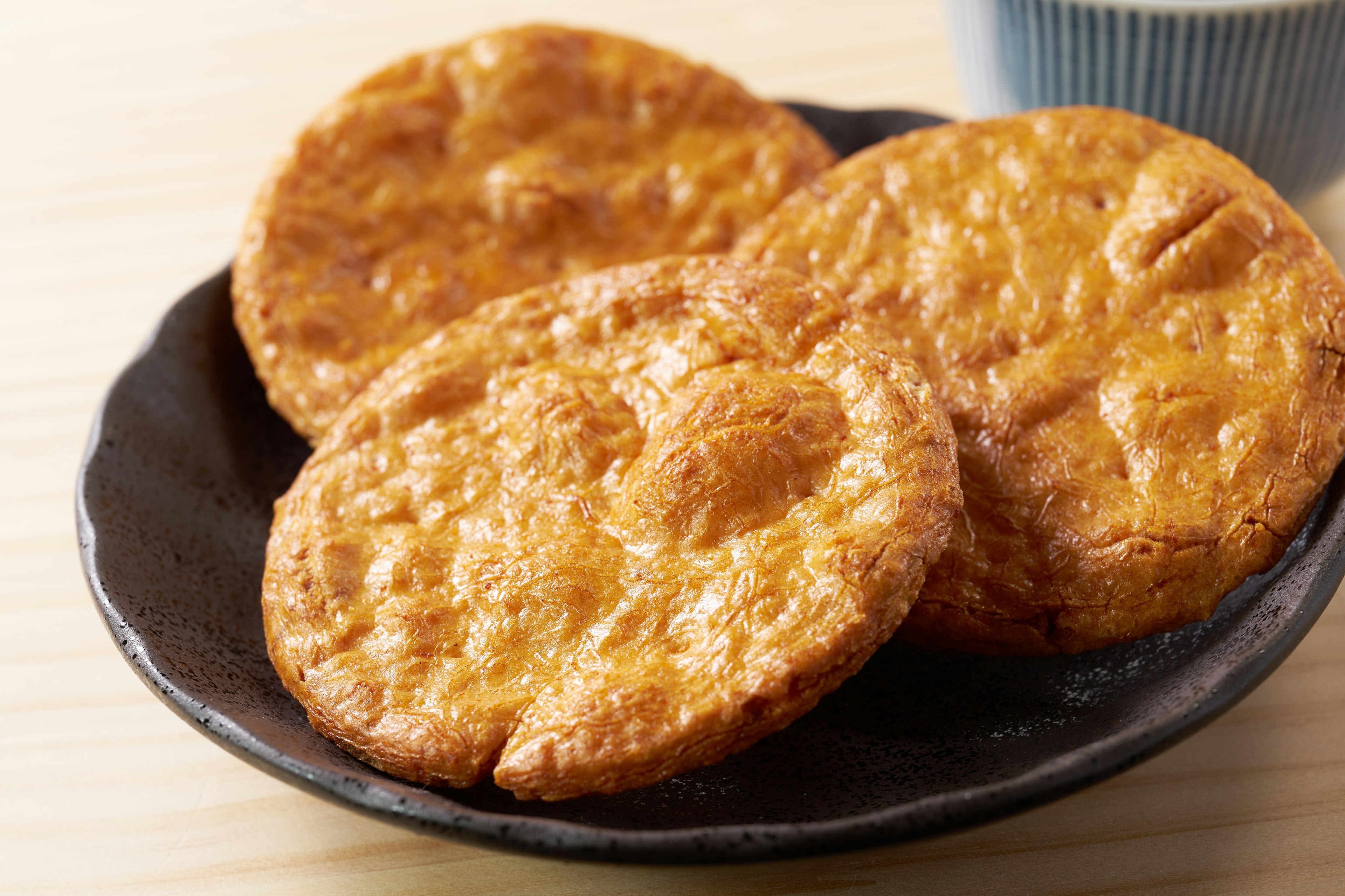 Three golden pastries on a black plate