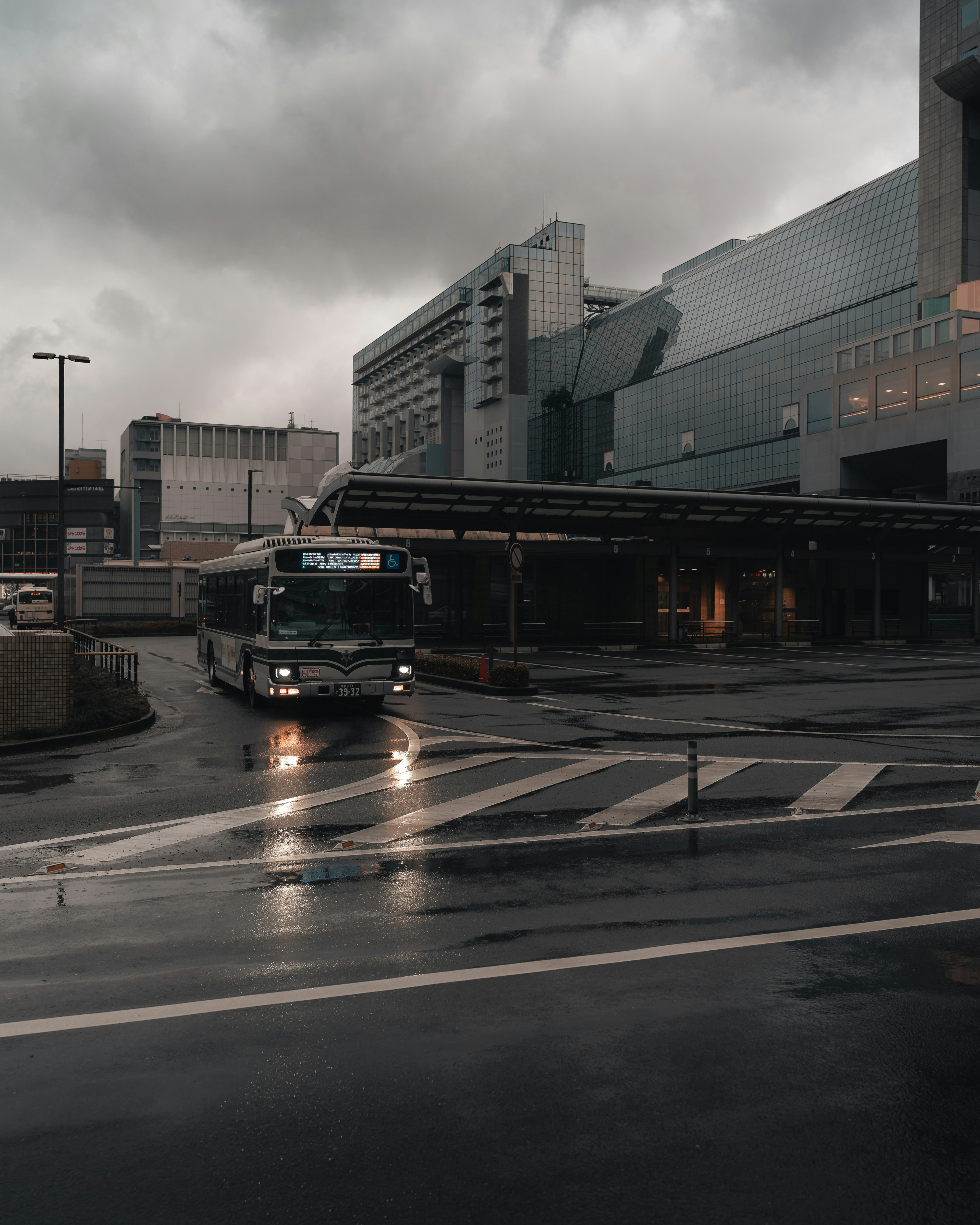 Bus driving through a rainy urban environment with modern buildings