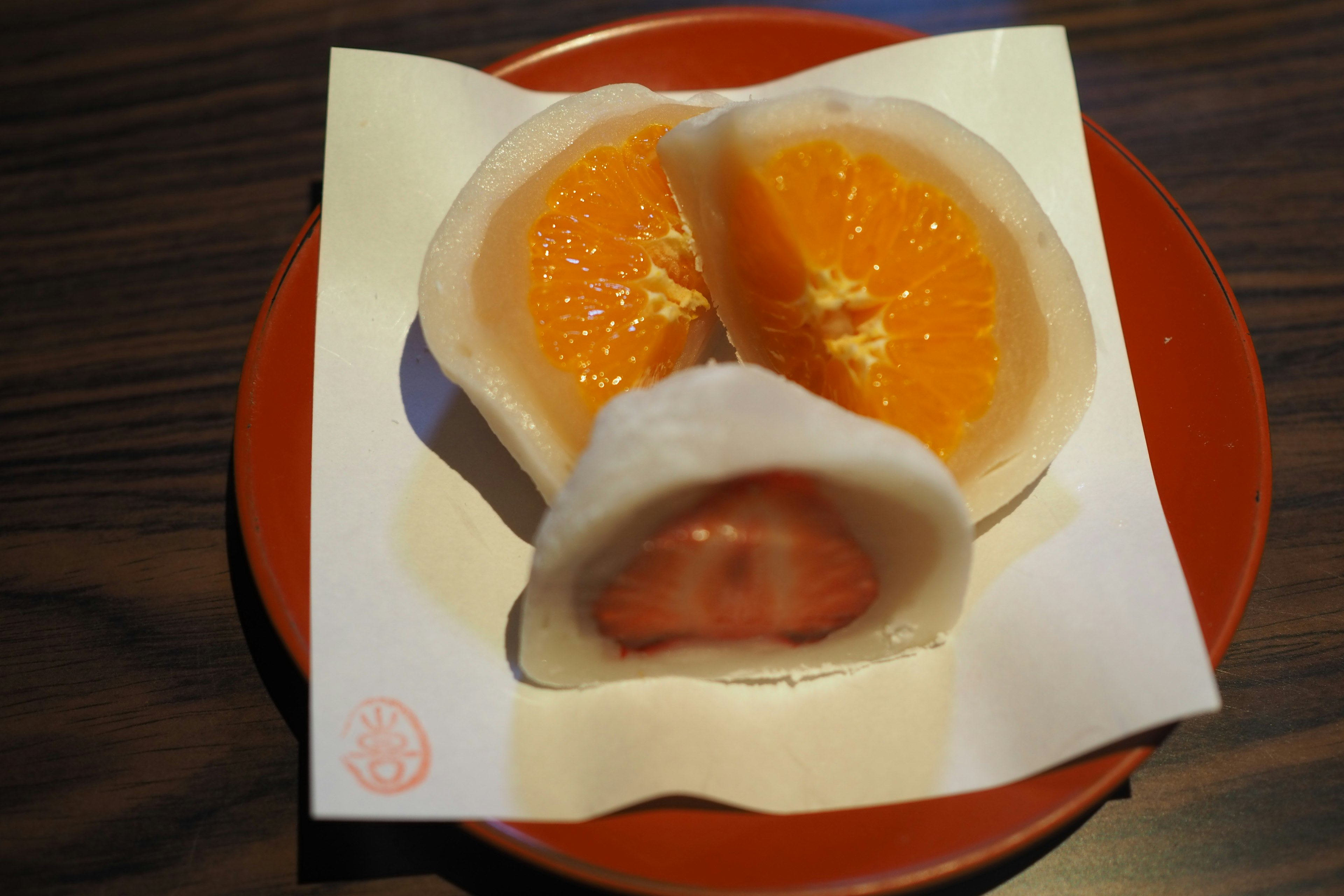 Sliced Japanese sweets filled with orange and strawberry on a plate