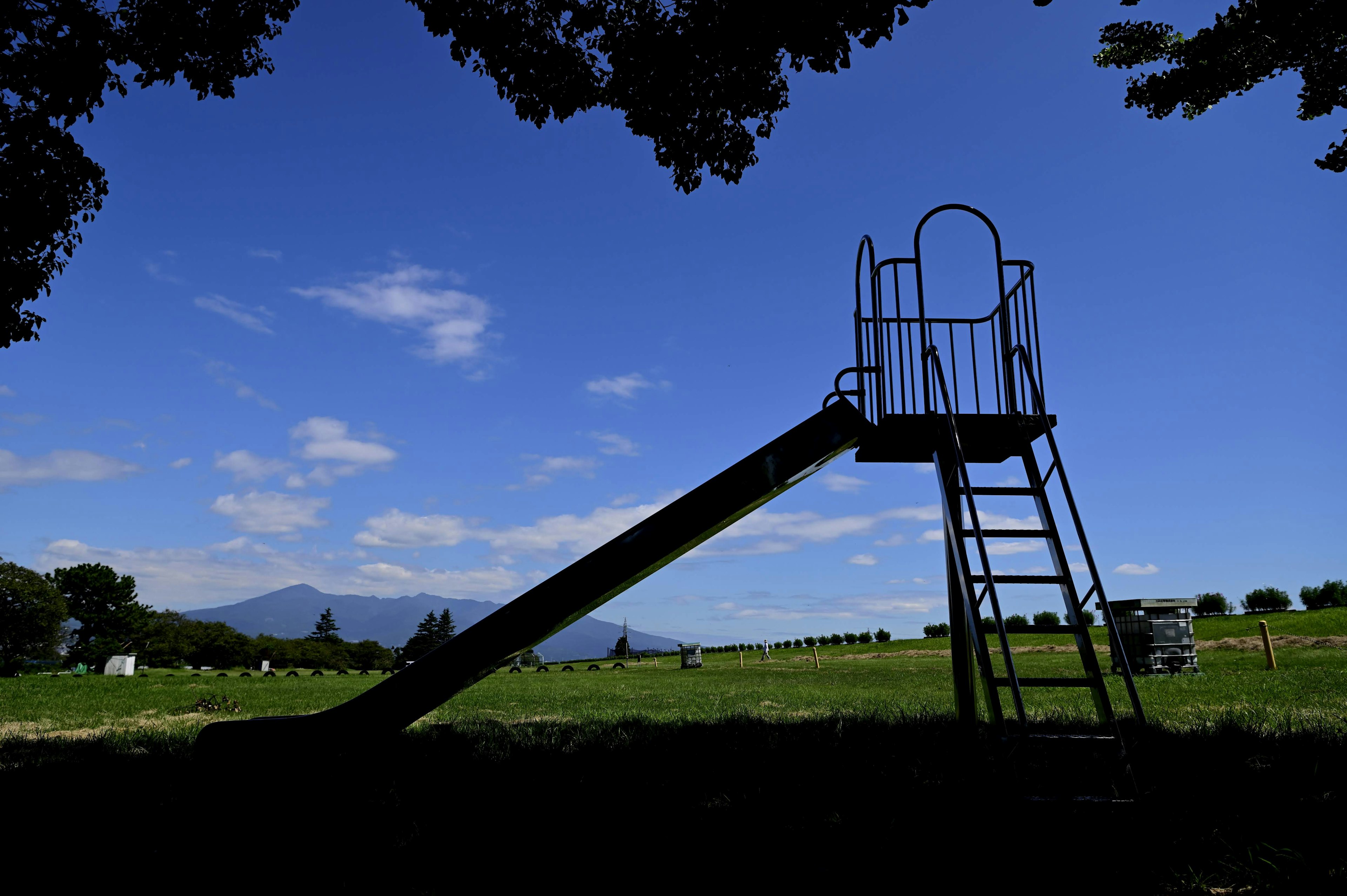 Struktur seluncur di bawah langit biru dengan rumput hijau