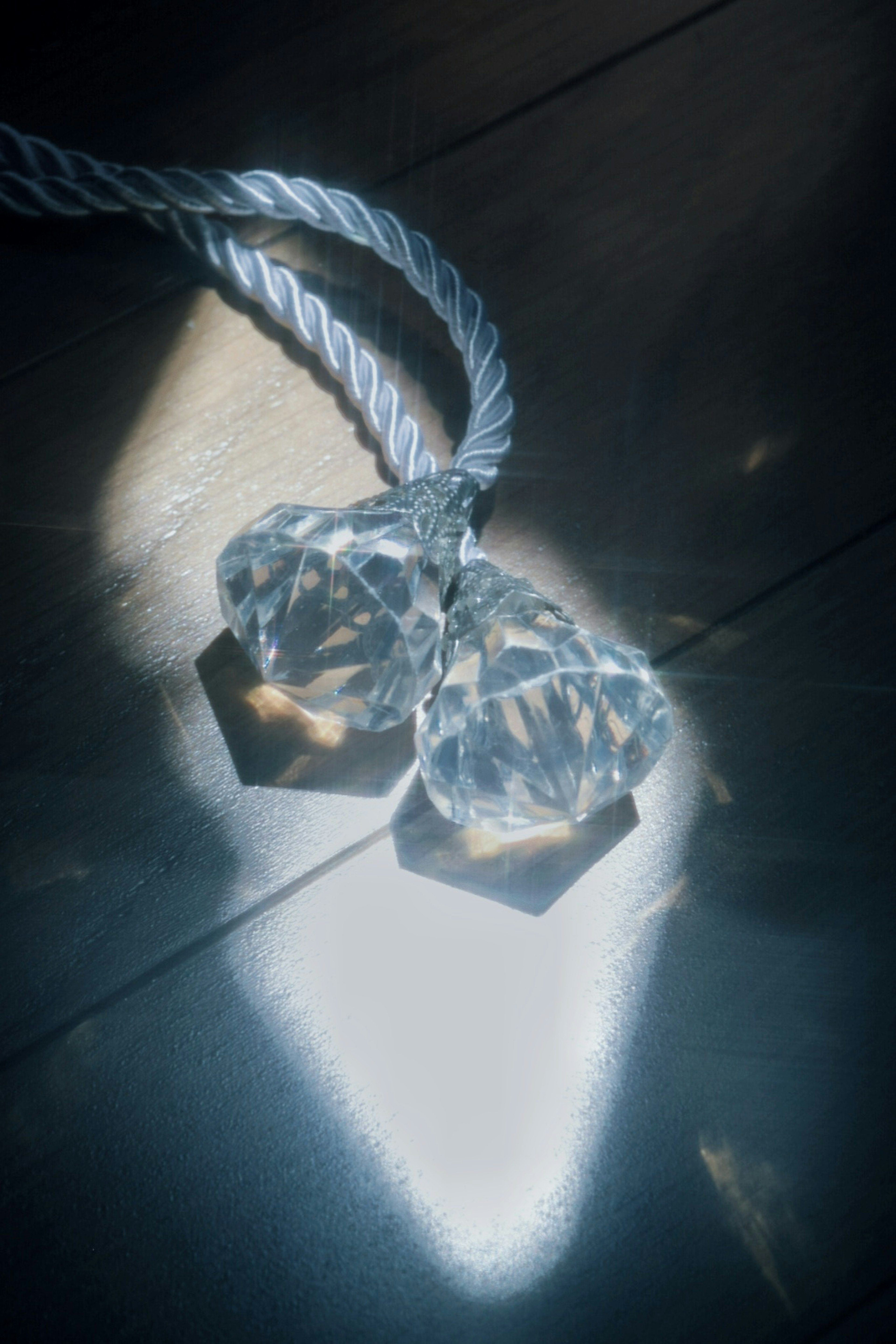 Two crystal heart-shaped objects reflecting light with a rope